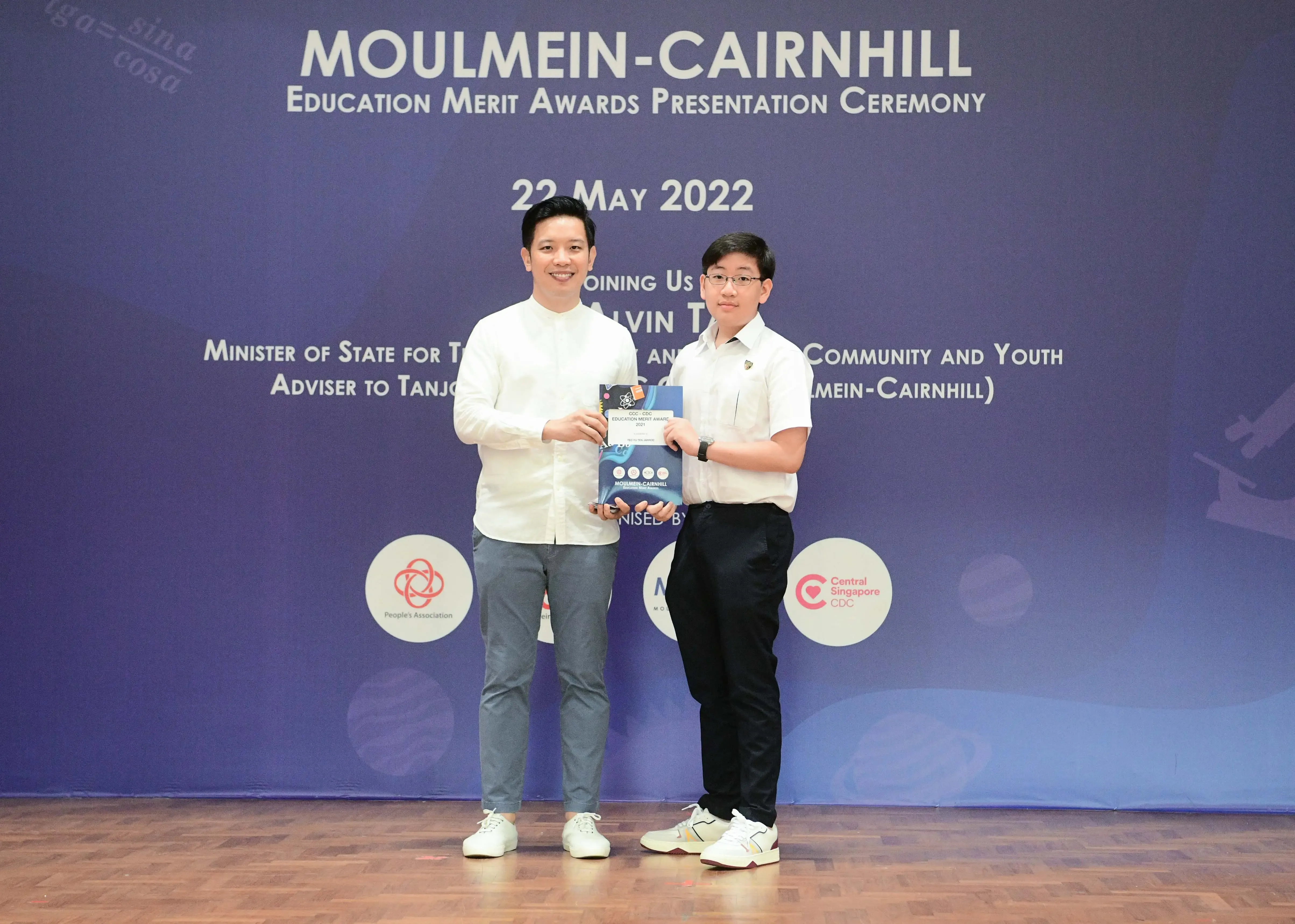 Two men hold an award booklet at the Moulmein-Cairnhill Education Merit Awards Ceremony on 22 May 2022.