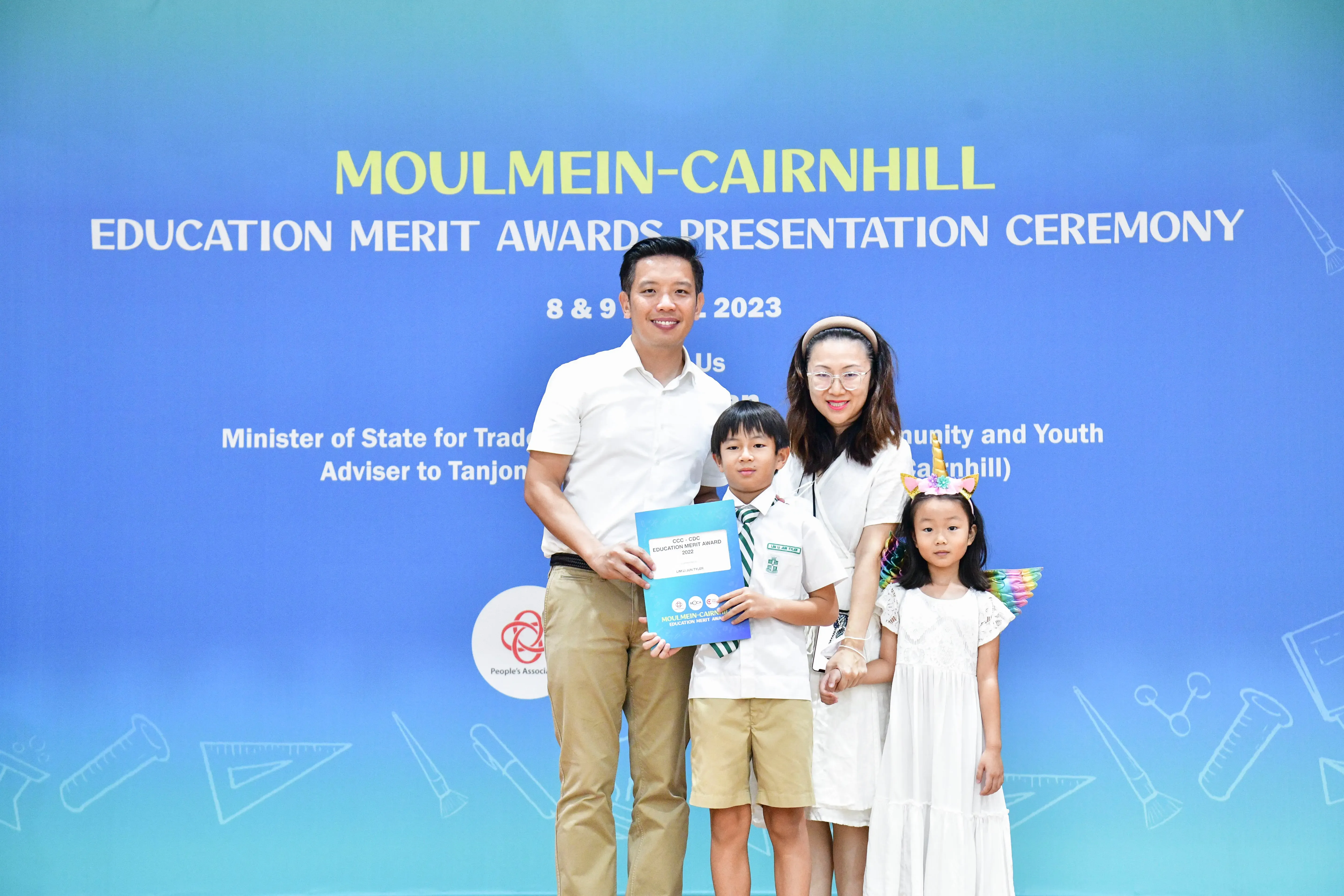 Family of four posing at Moulmein-Cairnhill Education Merit Awards Presentation Ceremony 2023, boy holding award certificate.
