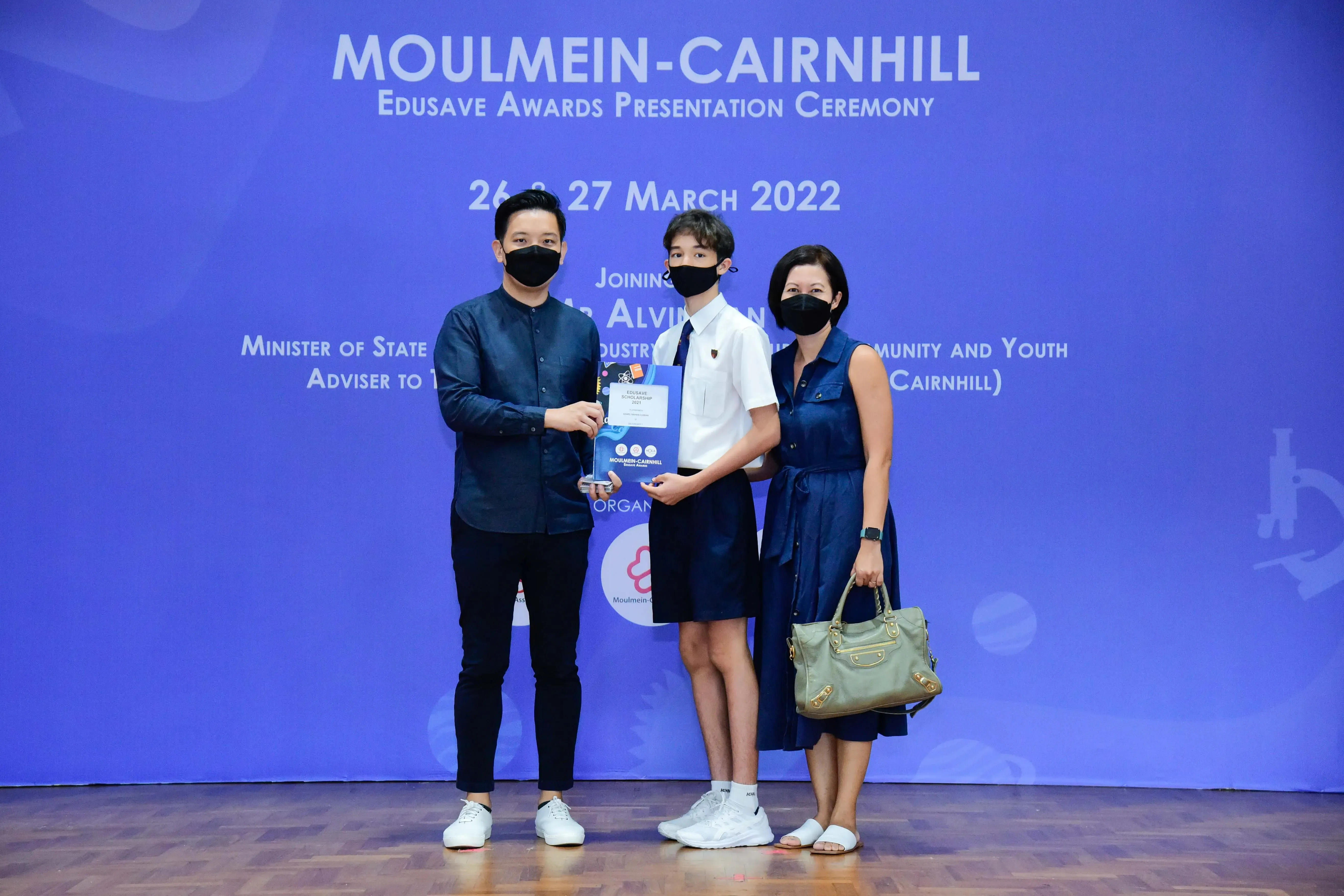 Three masked people pose at the Moulmein-Cairnhill Edusave Awards Ceremony on 26-27 March 2022.