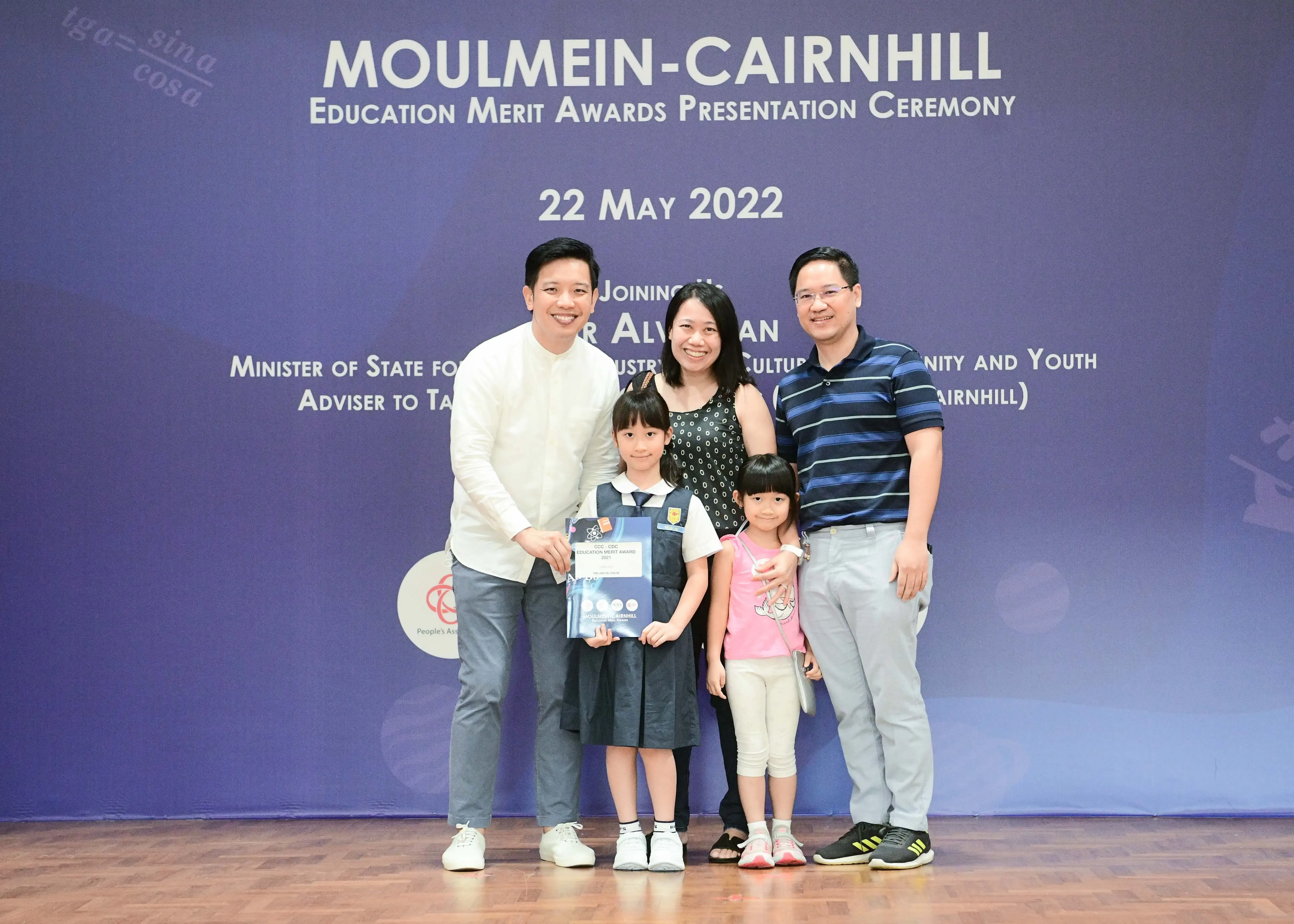 Family of five posing at the Moulmein-Cairnhill Education Merit Awards Ceremony on 22 May 2022, girl holding certificate.