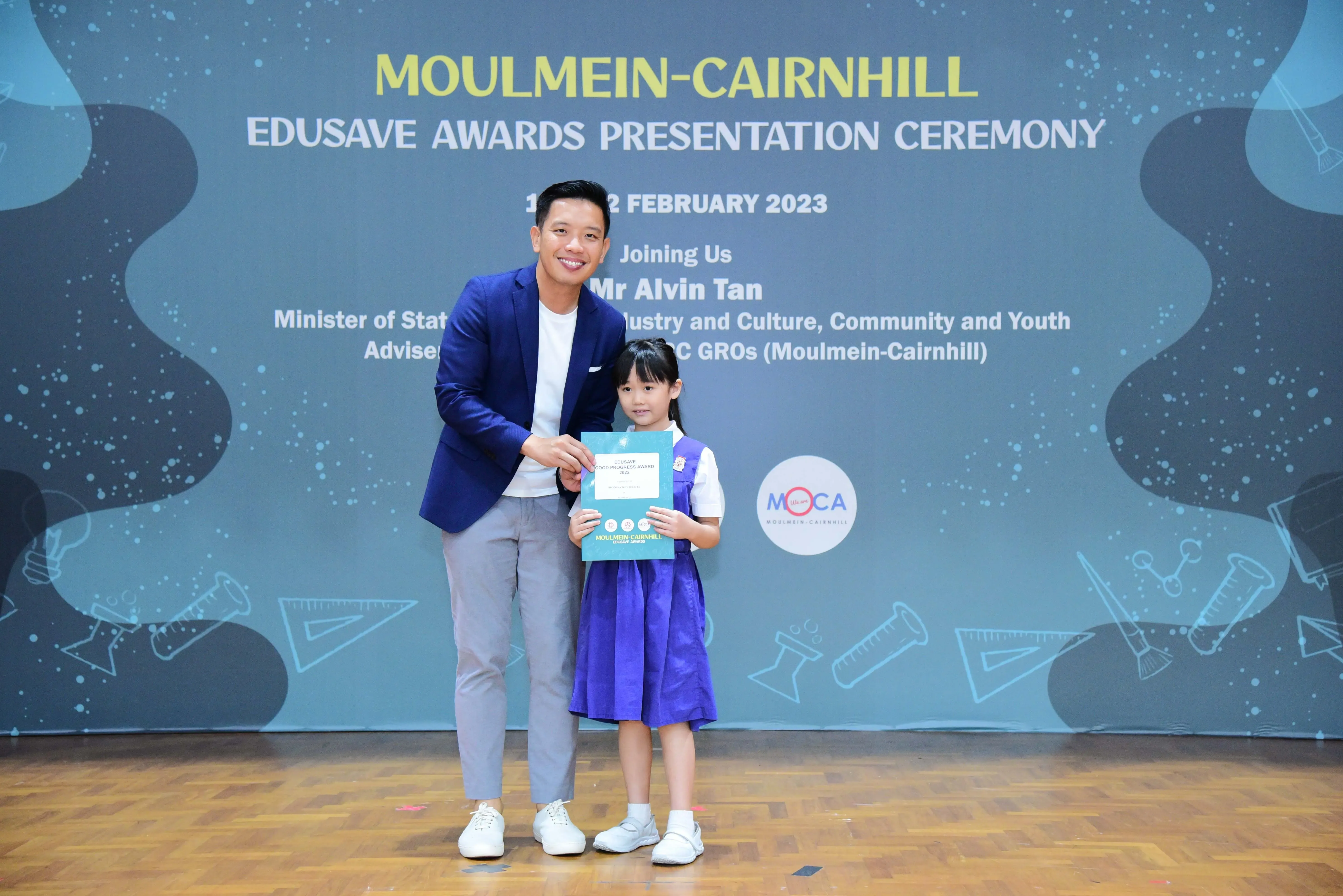 Man in blue blazer and young girl in school uniform hold a certificate at Moulmein-Cairnhill Edusave Awards 2023.