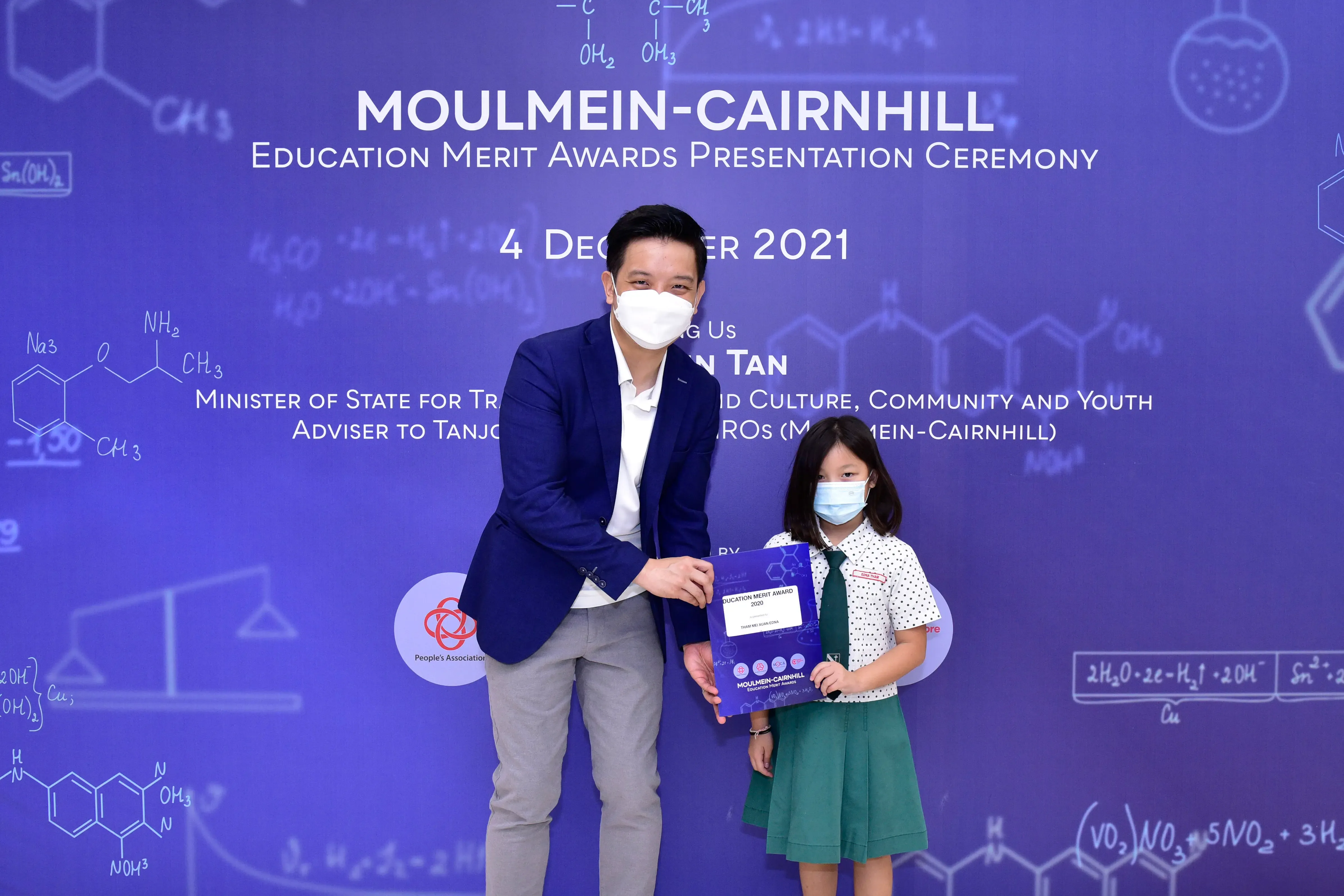 A man and a young girl wearing masks hold an award certificate at the Moulmein-Cairnhill Education Merit Awards 2021.