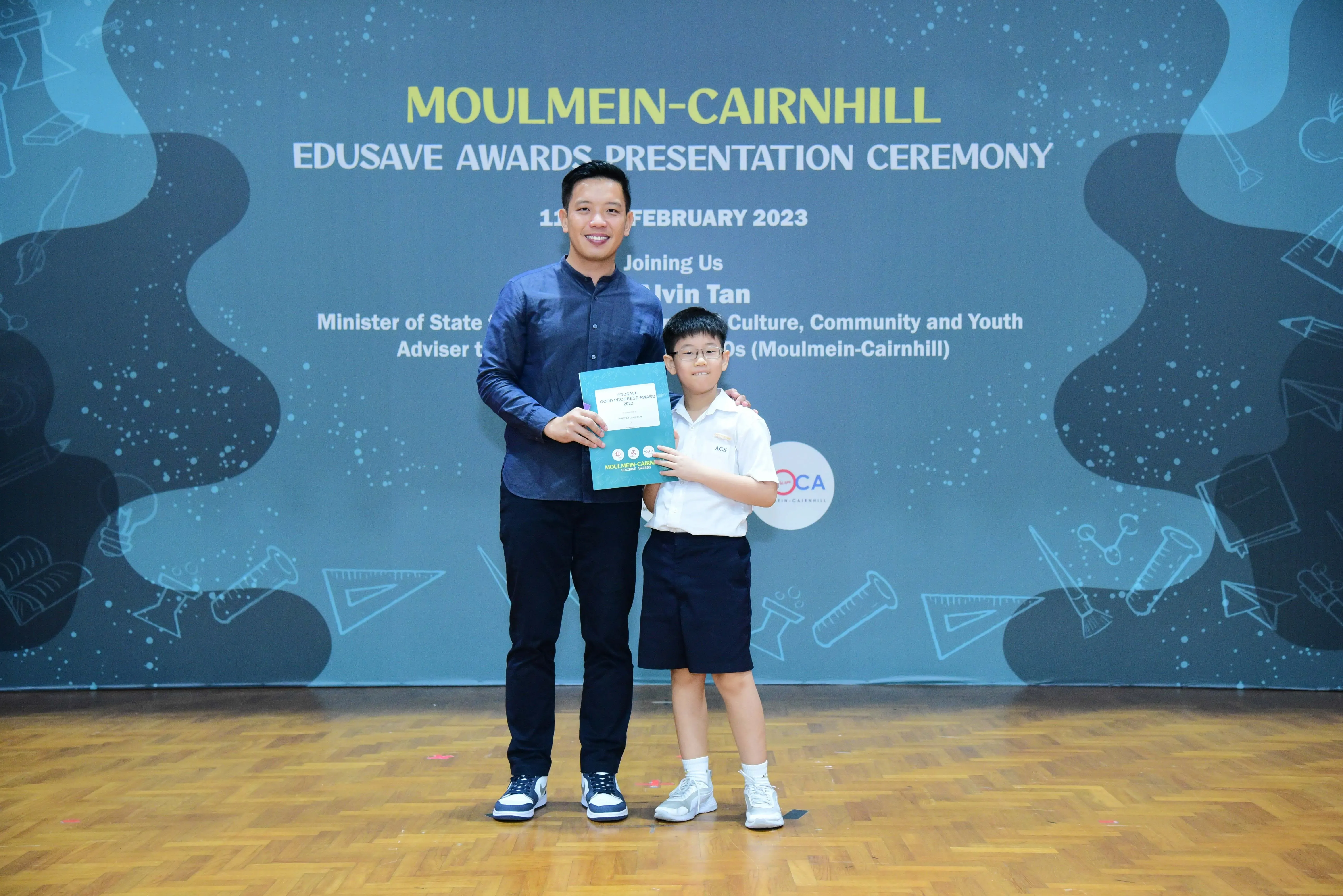 A man and a young boy pose together holding a certificate at the Moulmein-Cairnhill Edusave Awards Ceremony 2023.