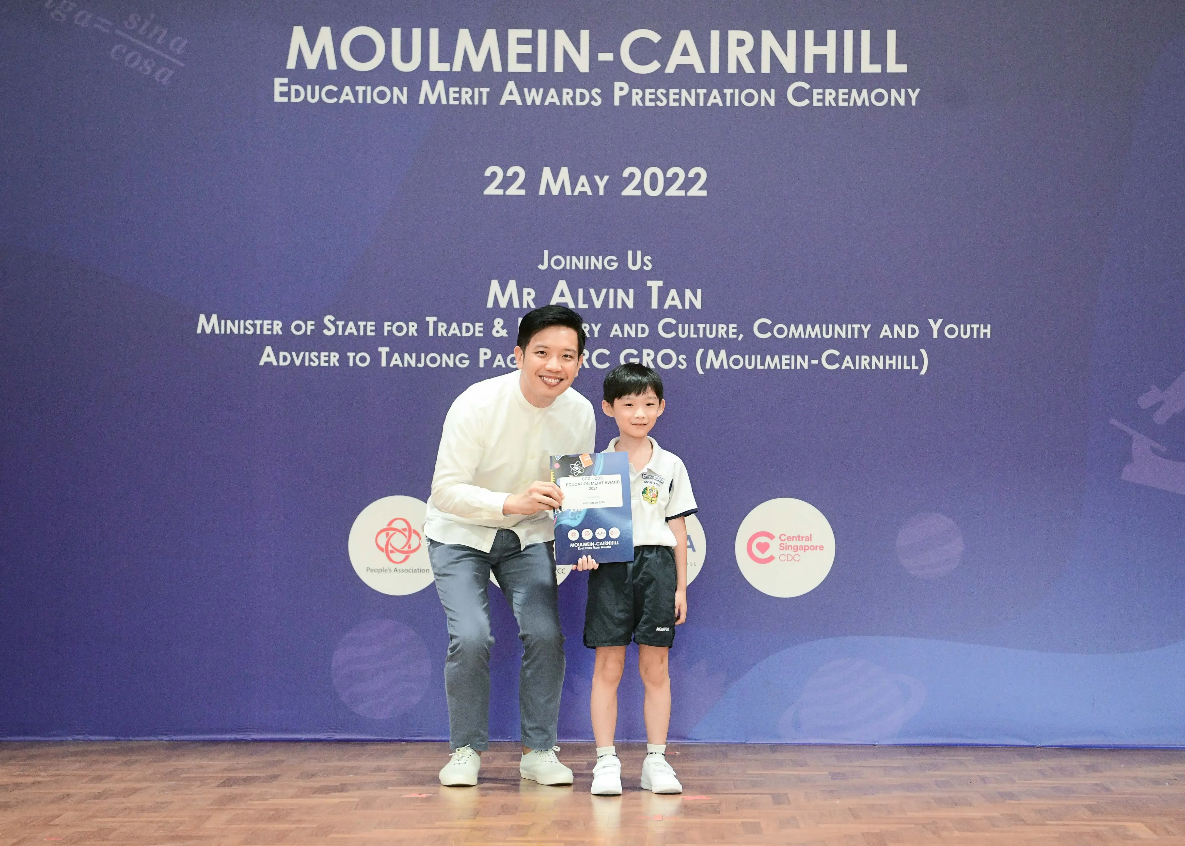 Man and young boy hold an award certificate at Moulmein-Cairnhill Education Merit Awards Ceremony, 22 May 2022.