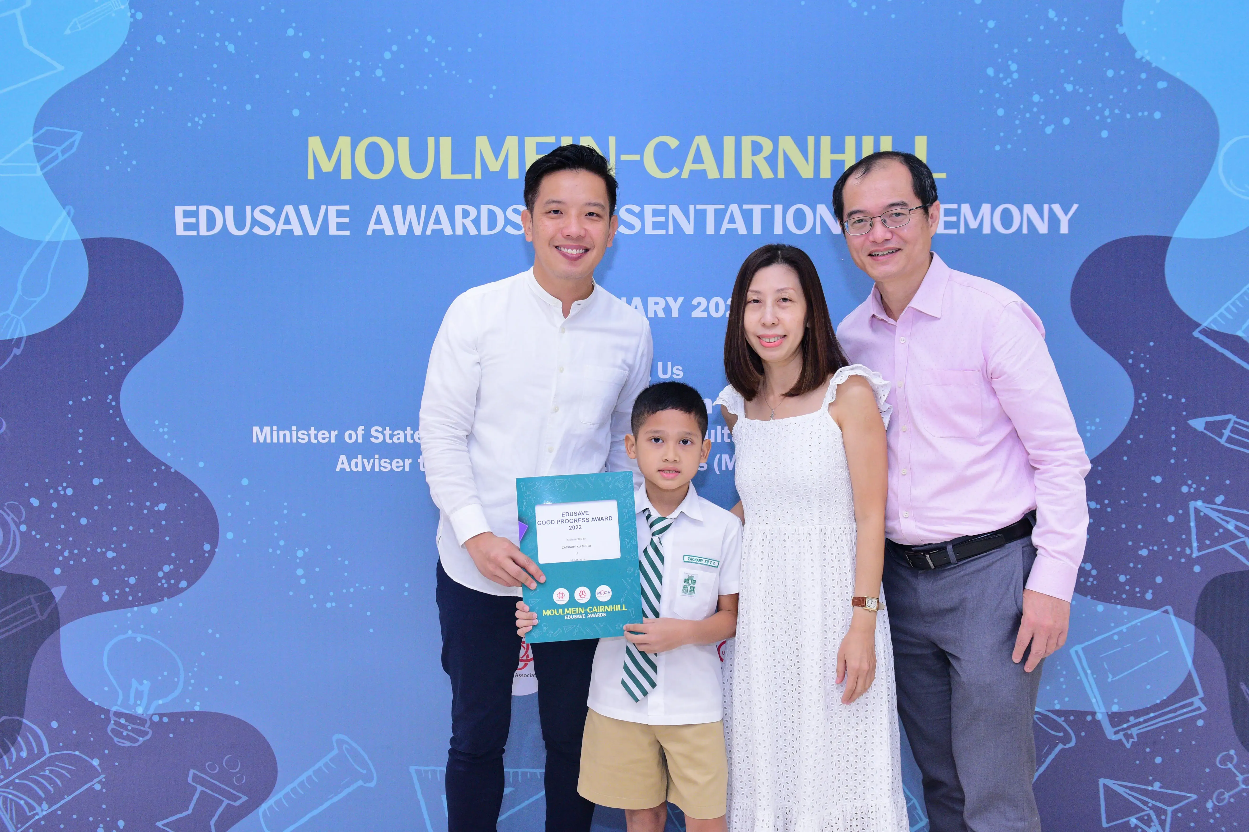 Three adults and a young boy holding an Edusave Good Progress Award certificate at the Moulmein-Cairnhill ceremony.