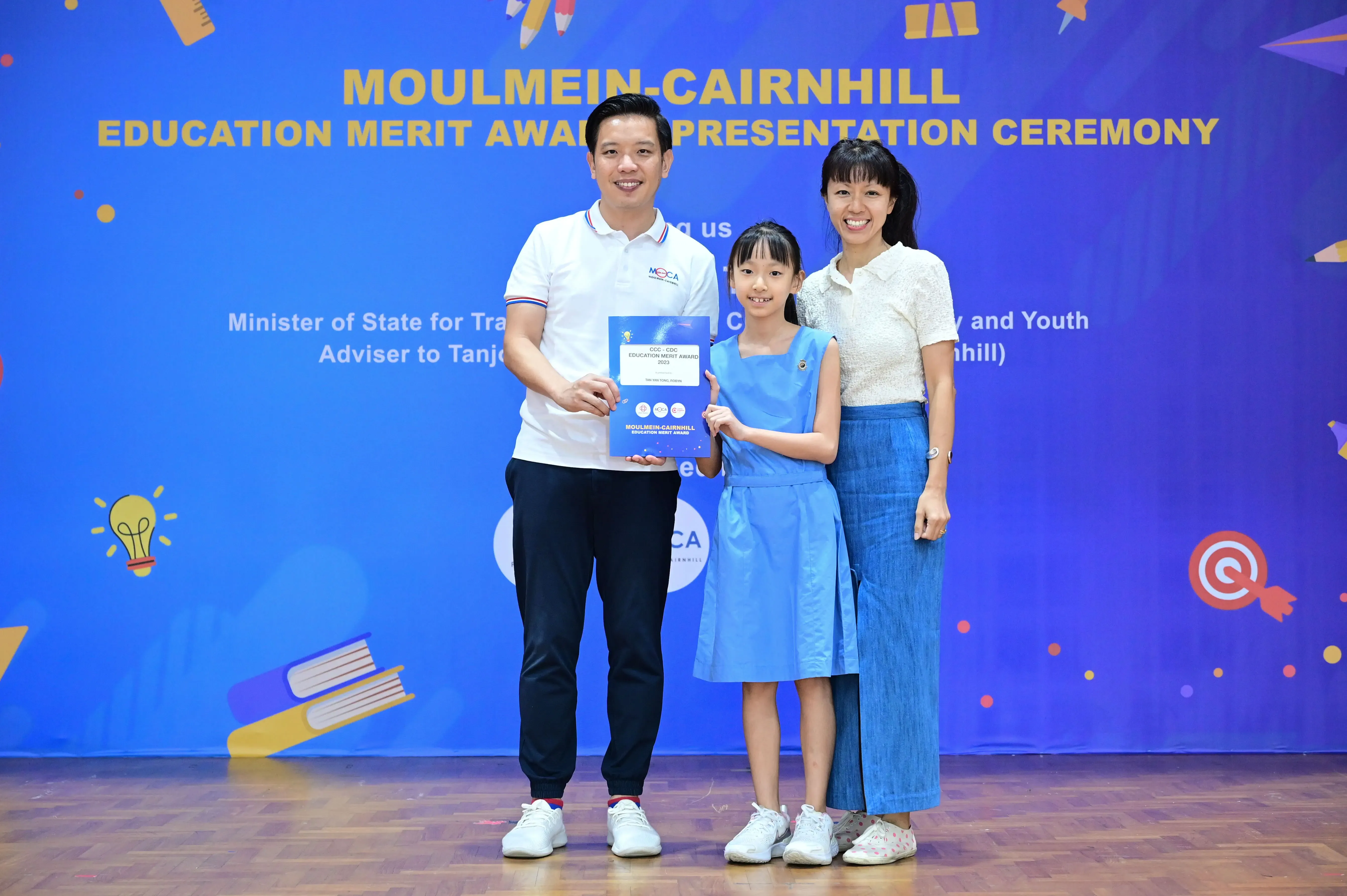 Three people pose with an award certificate at the Moulmein-Cairnhill Education Merit Award Presentation Ceremony.