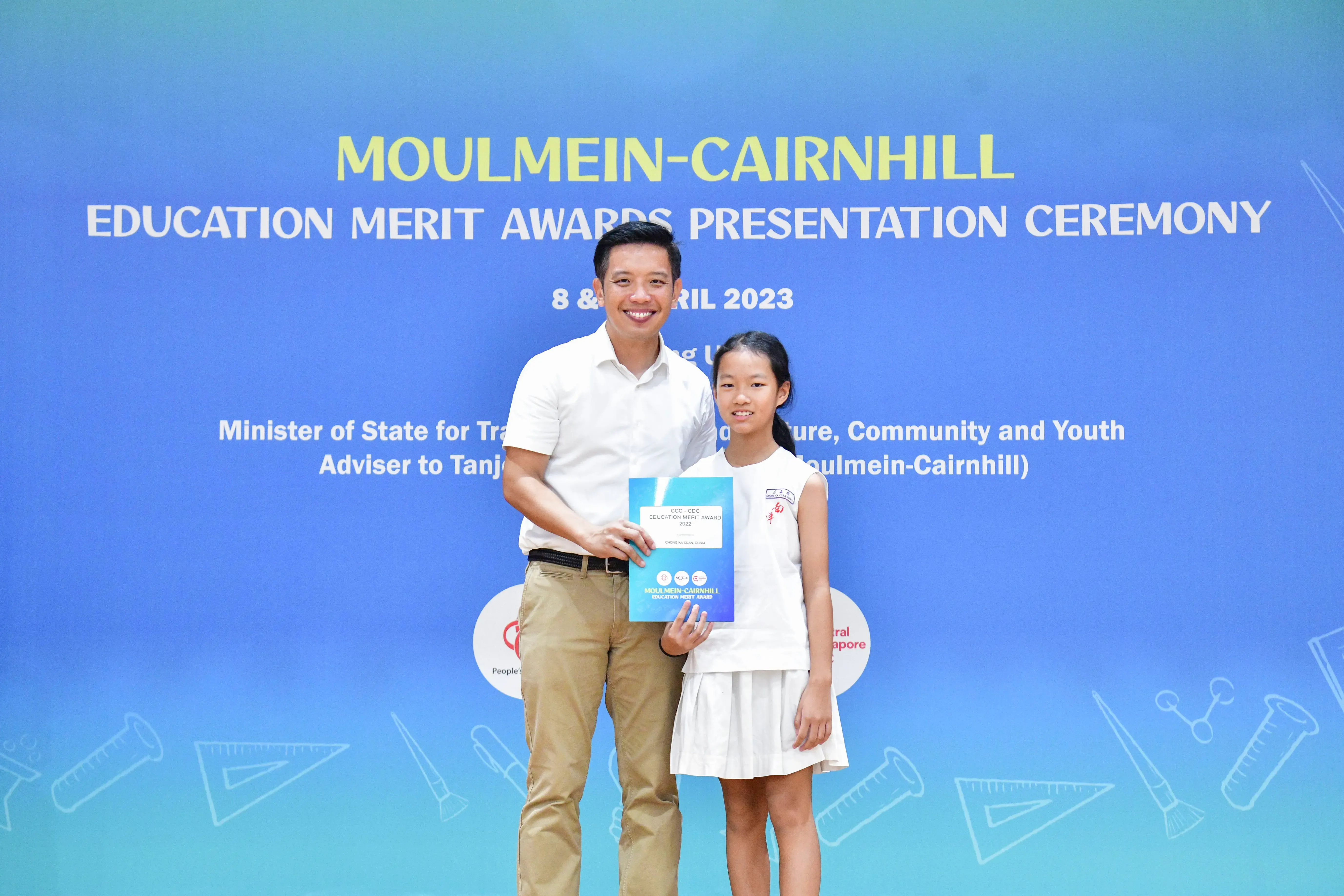 A man and a young girl pose together holding an award certificate at the Moulmein-Cairnhill Education Merit Awards 2023.