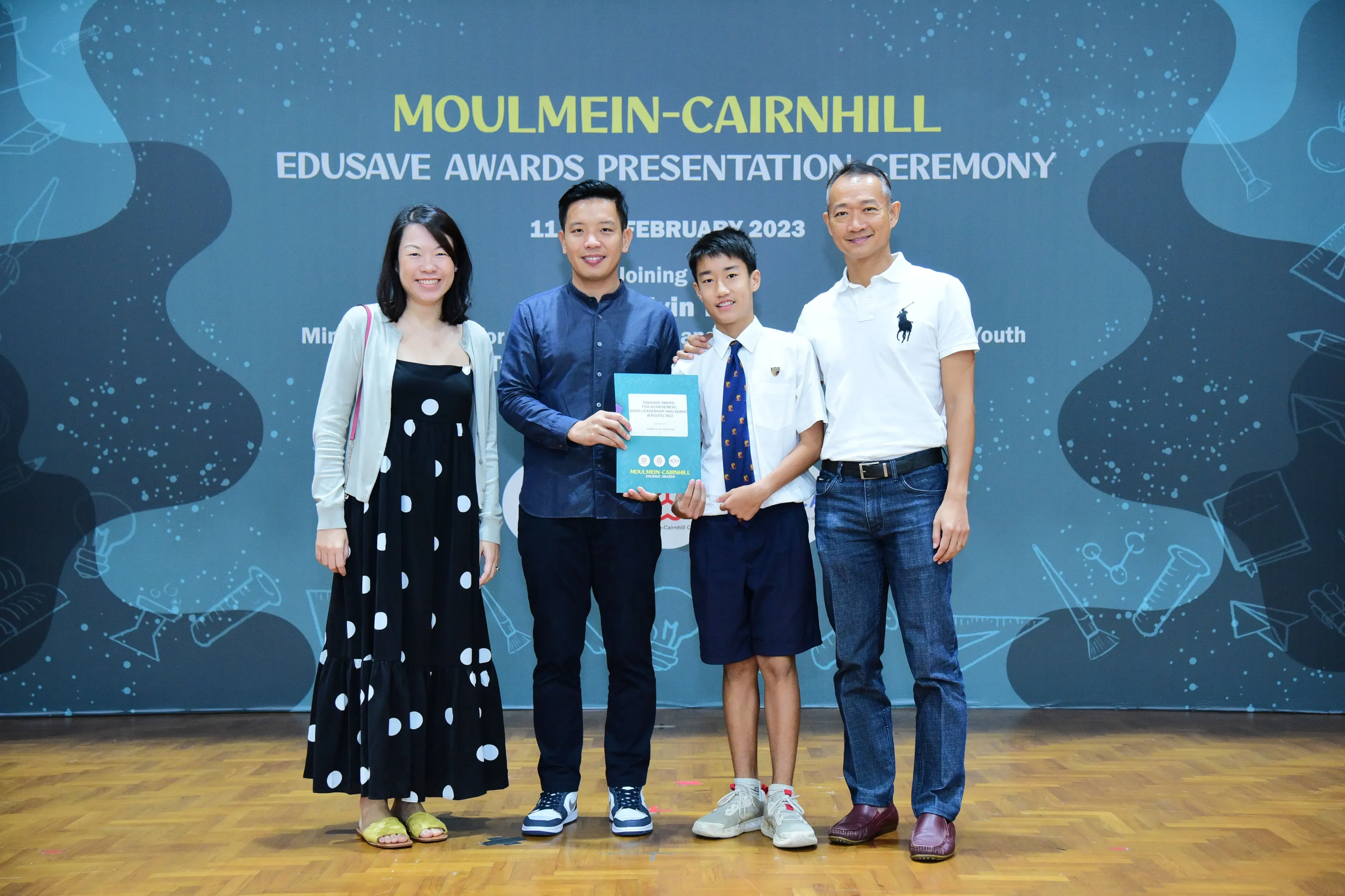 Four people pose at the Moulmein-Cairnhill Edusave Awards Presentation Ceremony in February 2023, holding a certificate.