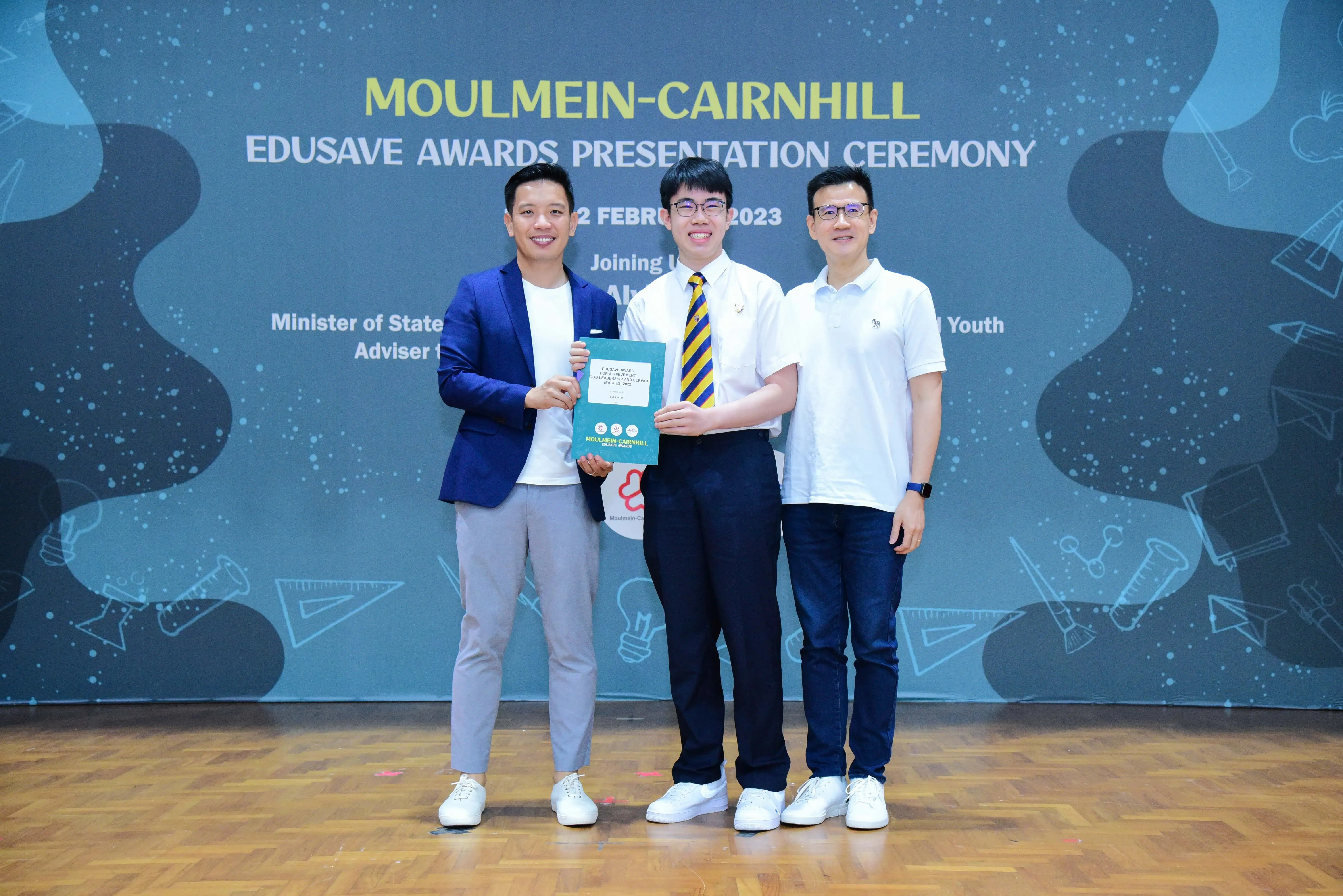 Three people pose holding a certificate at the Moulmein-Cairnhill Edusave Awards Presentation Ceremony 2023.