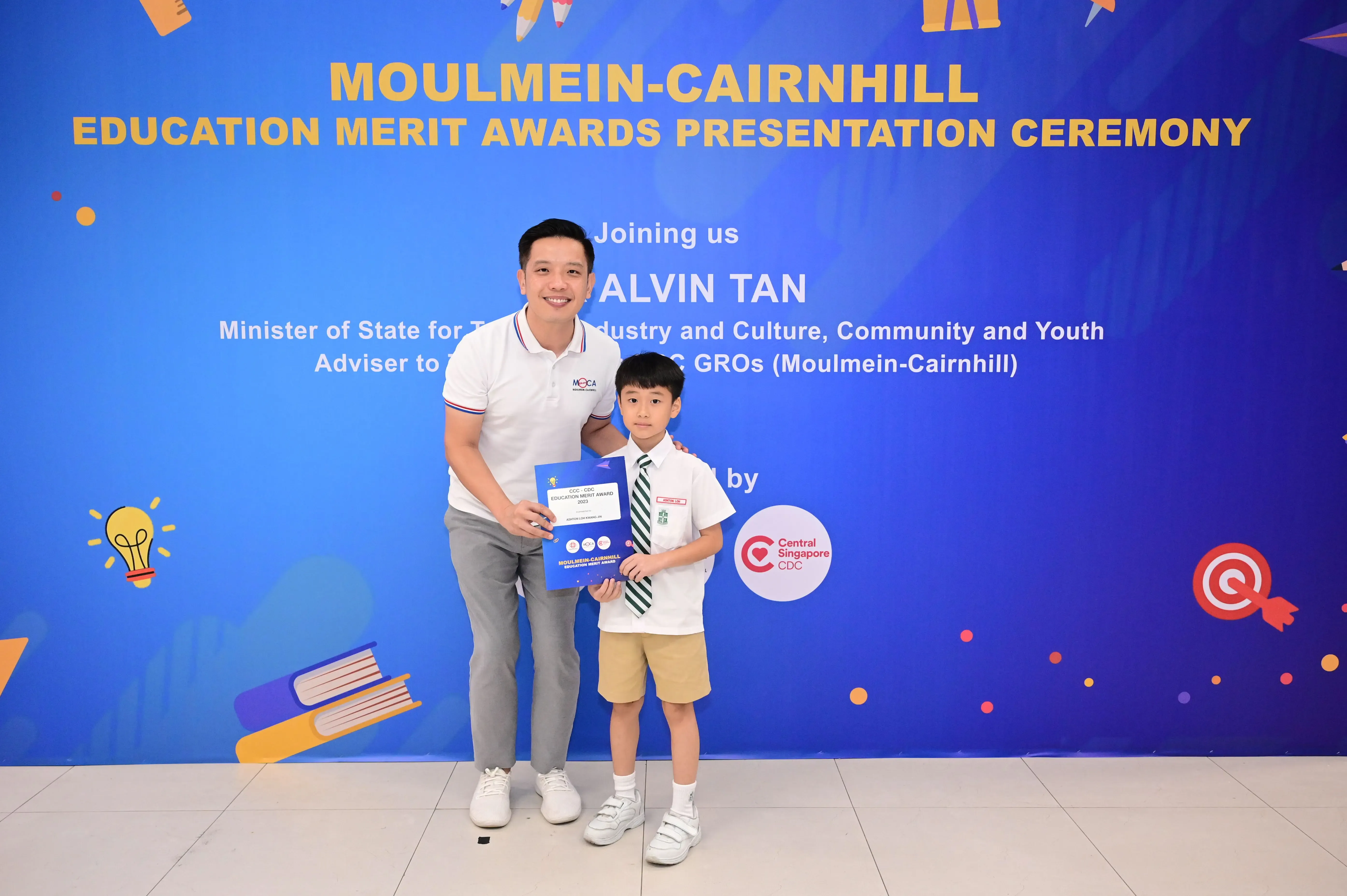 Man and young boy holding an award certificate at the Moulmein-Cairnhill Education Merit Awards Ceremony.