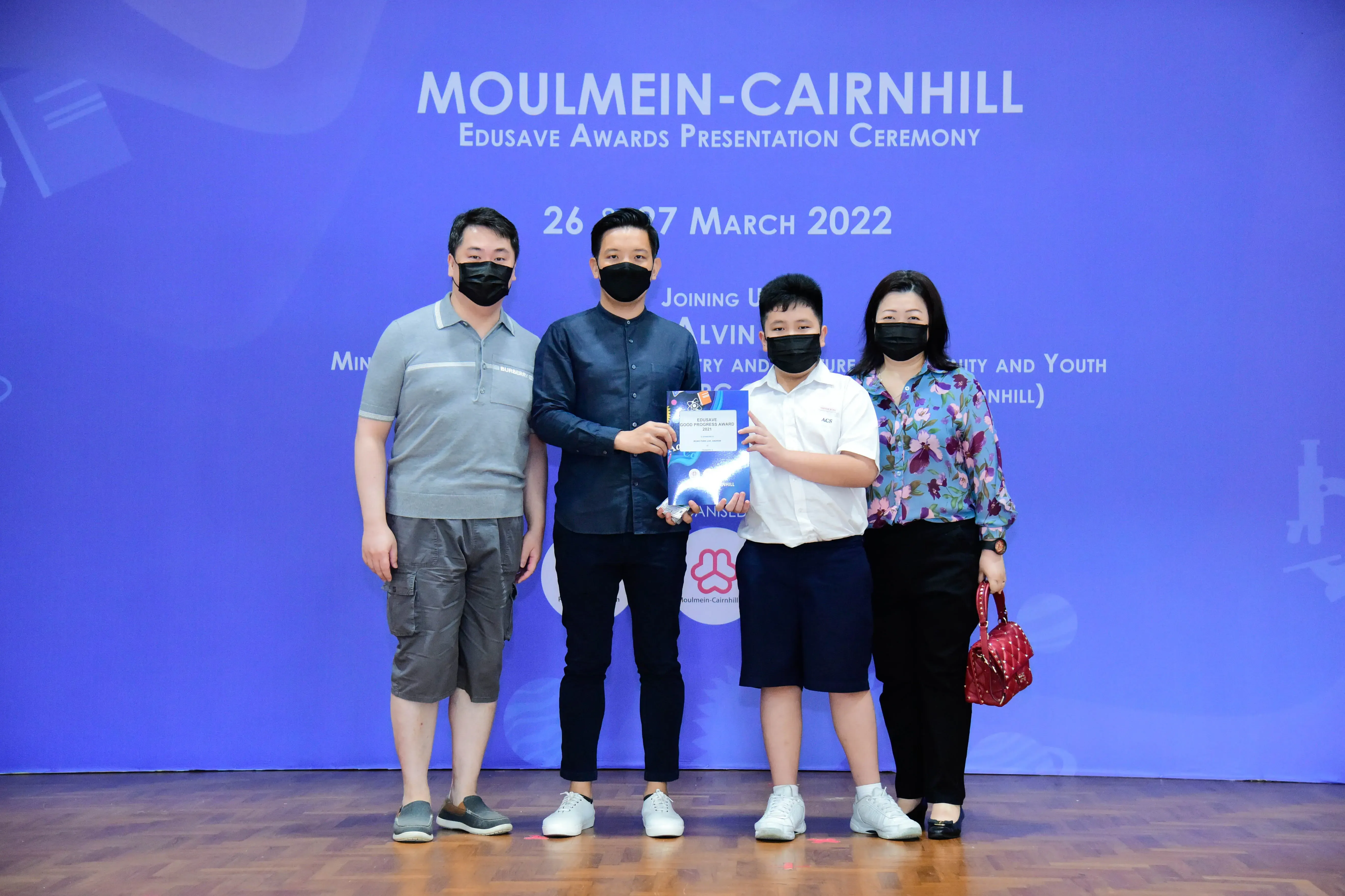 Four masked people pose at the Moulmein-Cairnhill Edusave Awards Presentation Ceremony on 26-27 March 2022.