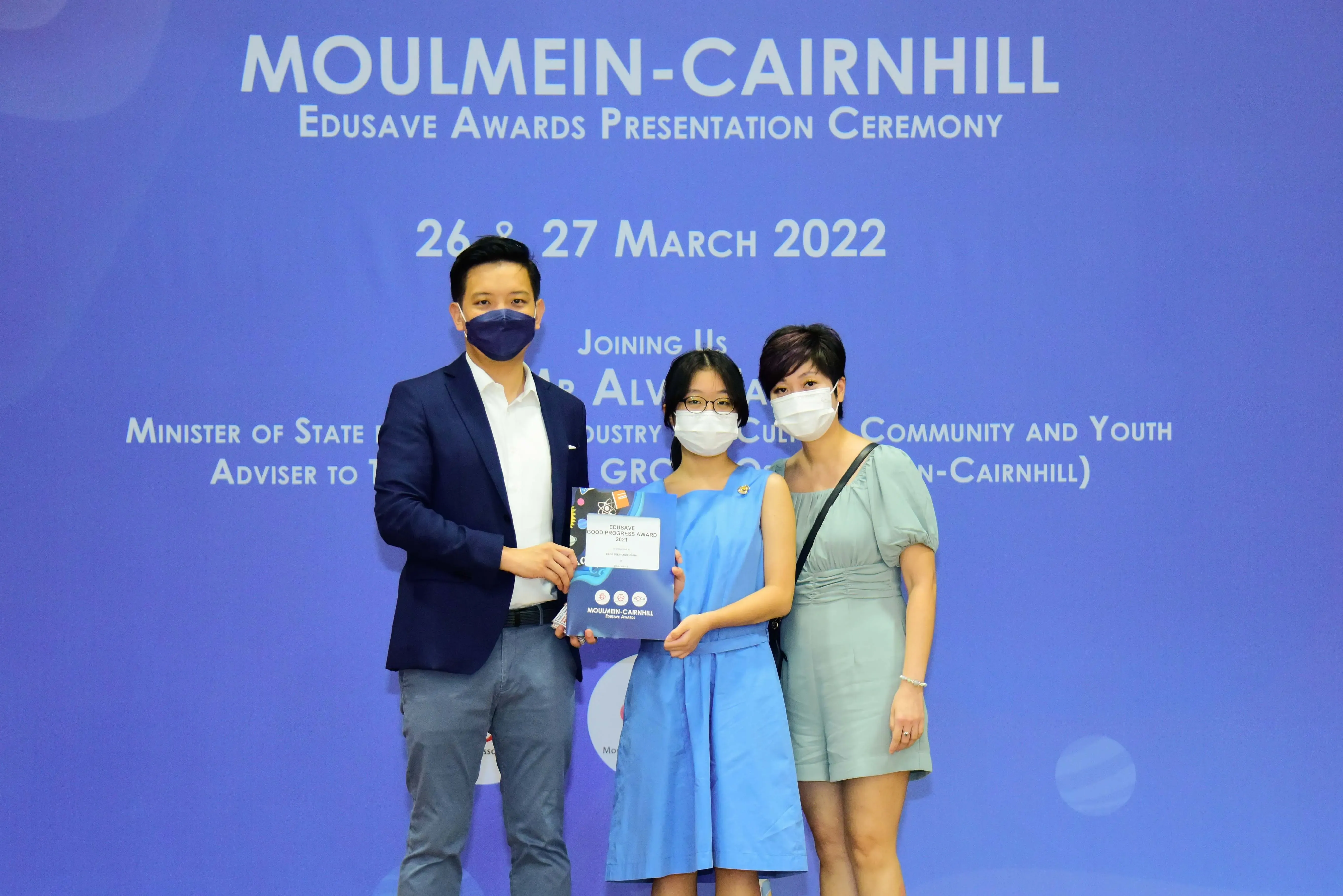 Three masked people pose with an award certificate at the Moulmein-Cairnhill Edusave Awards Ceremony, March 2022.