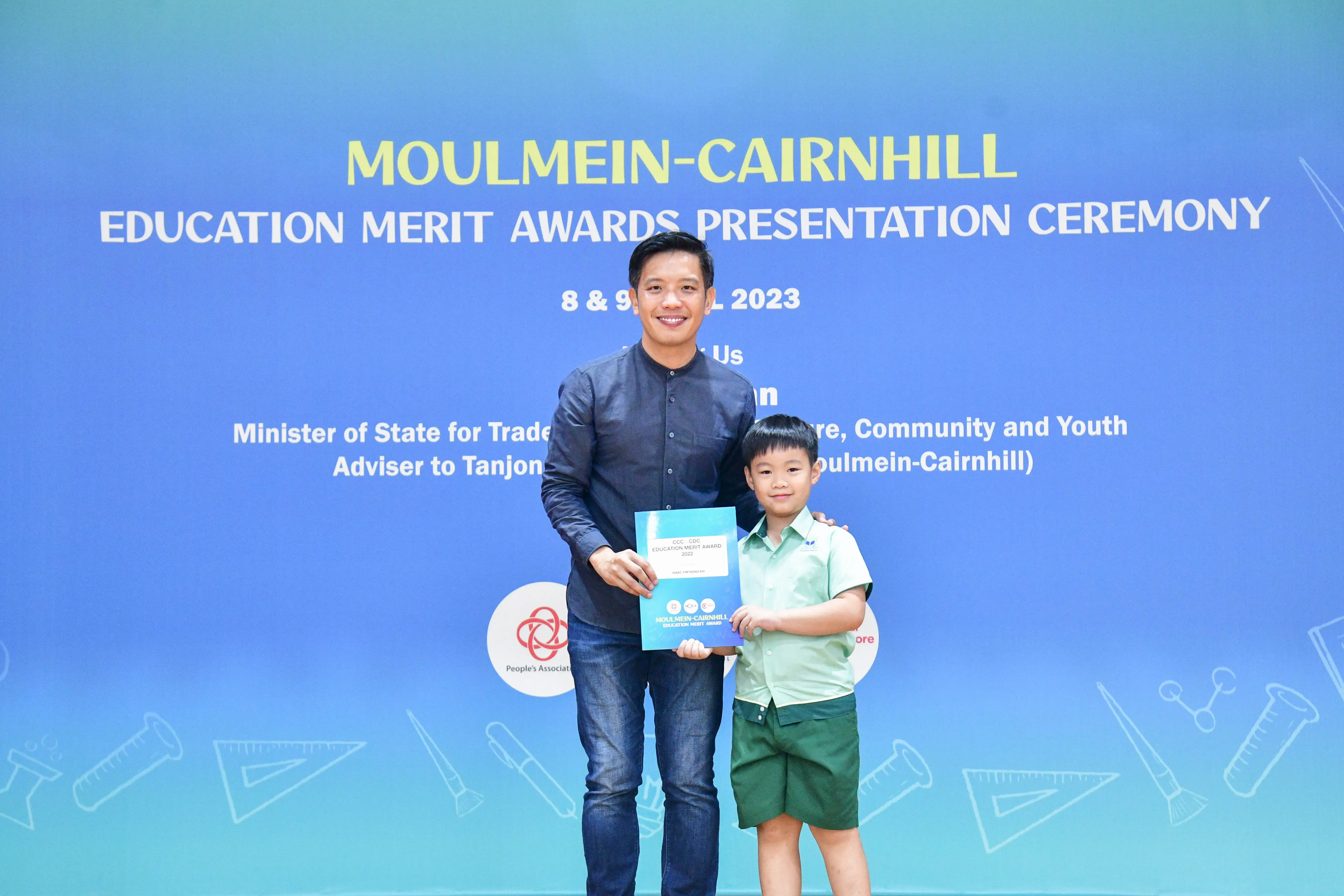 A man and a young boy pose together holding a certificate at the Moulmein-Cairnhill Education Merit Awards Ceremony 2023.