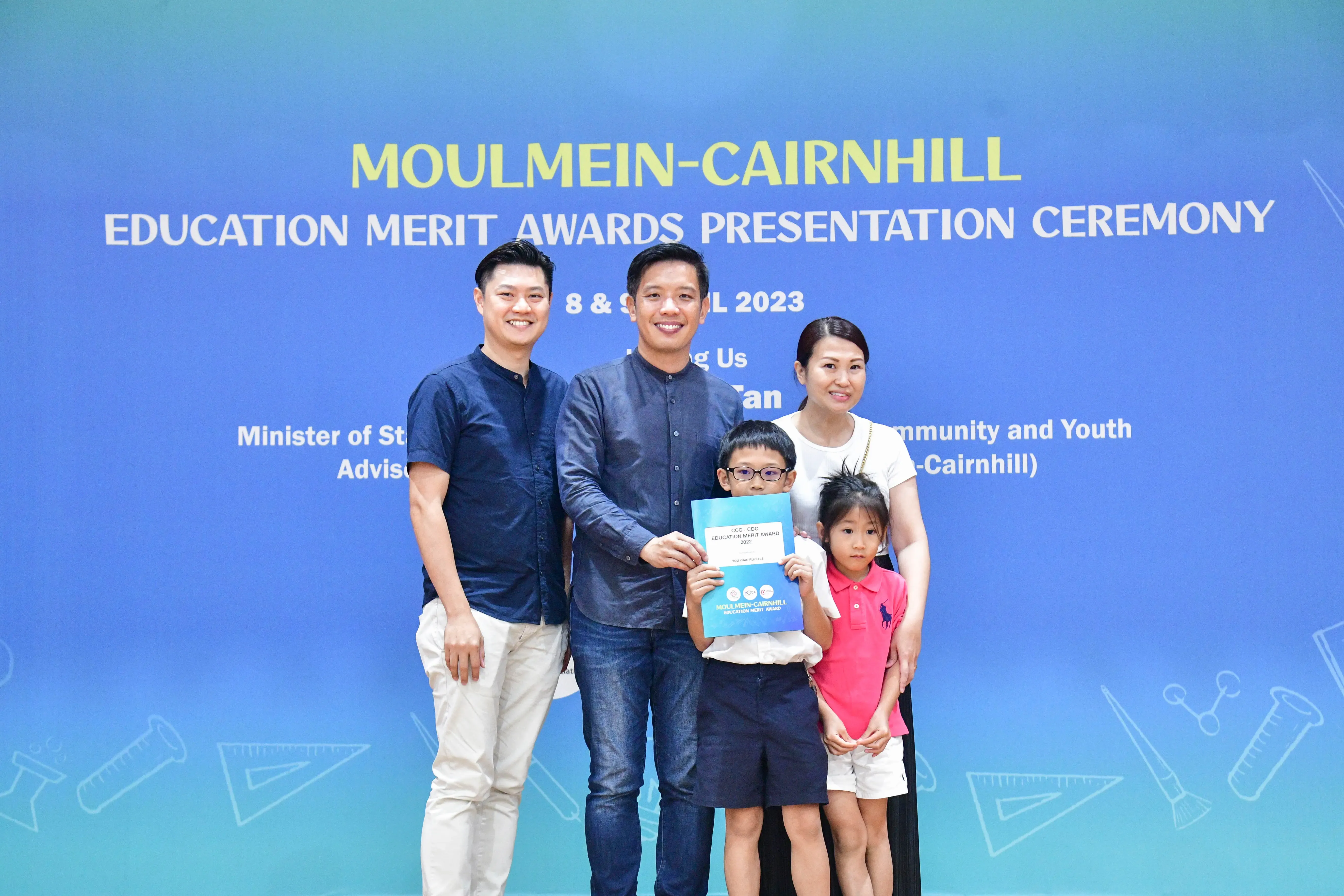 Two men, a woman, and two children pose with a certificate at the Moulmein-Cairnhill Education Merit Awards 2023.