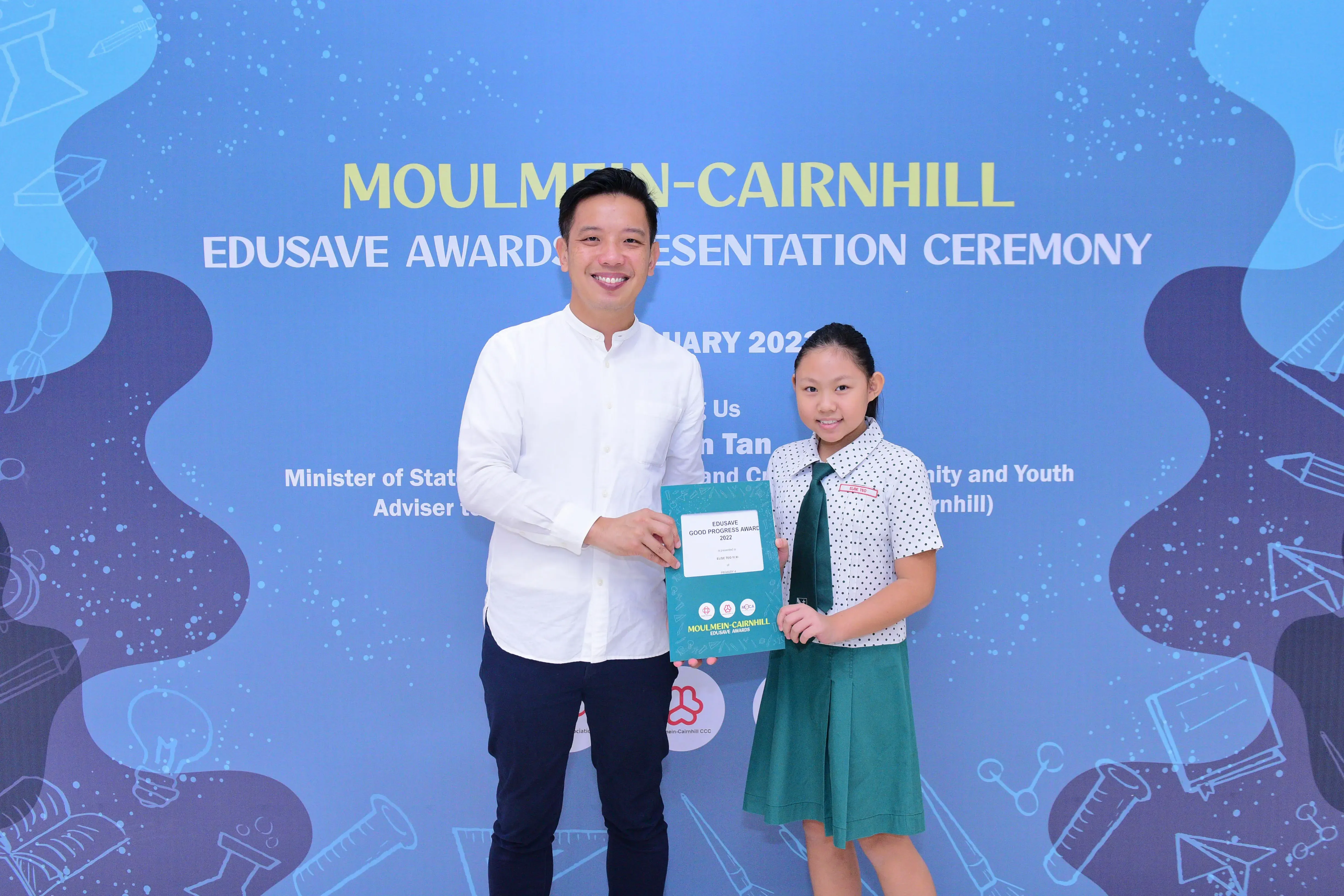 A man and a young girl hold a certificate together at the Moulmein-Cairnhill Edusave Awards Presentation Ceremony.