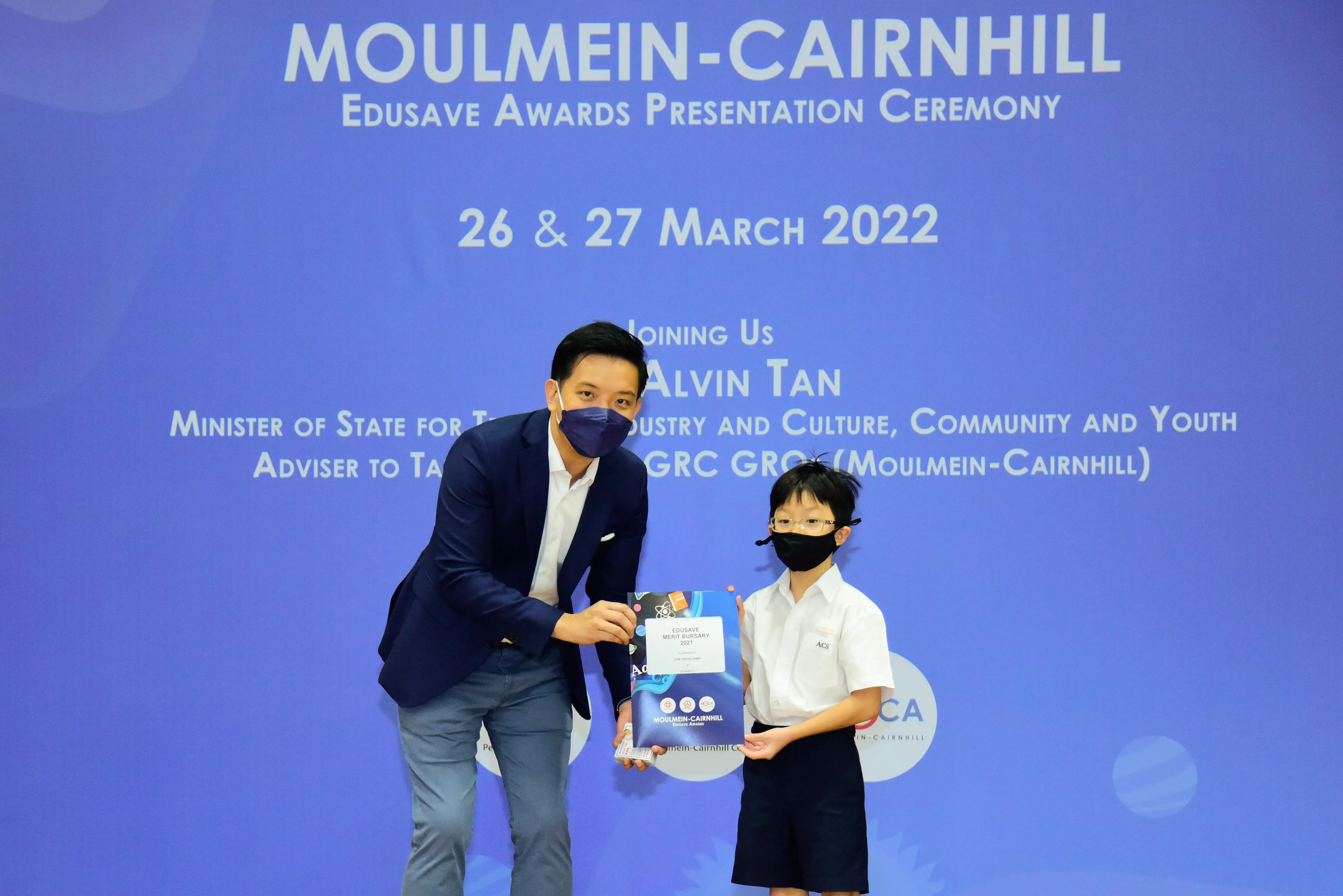An adult and a young student hold an award certificate at the Moulmein-Cairnhill Edusave Awards Ceremony in 2022.