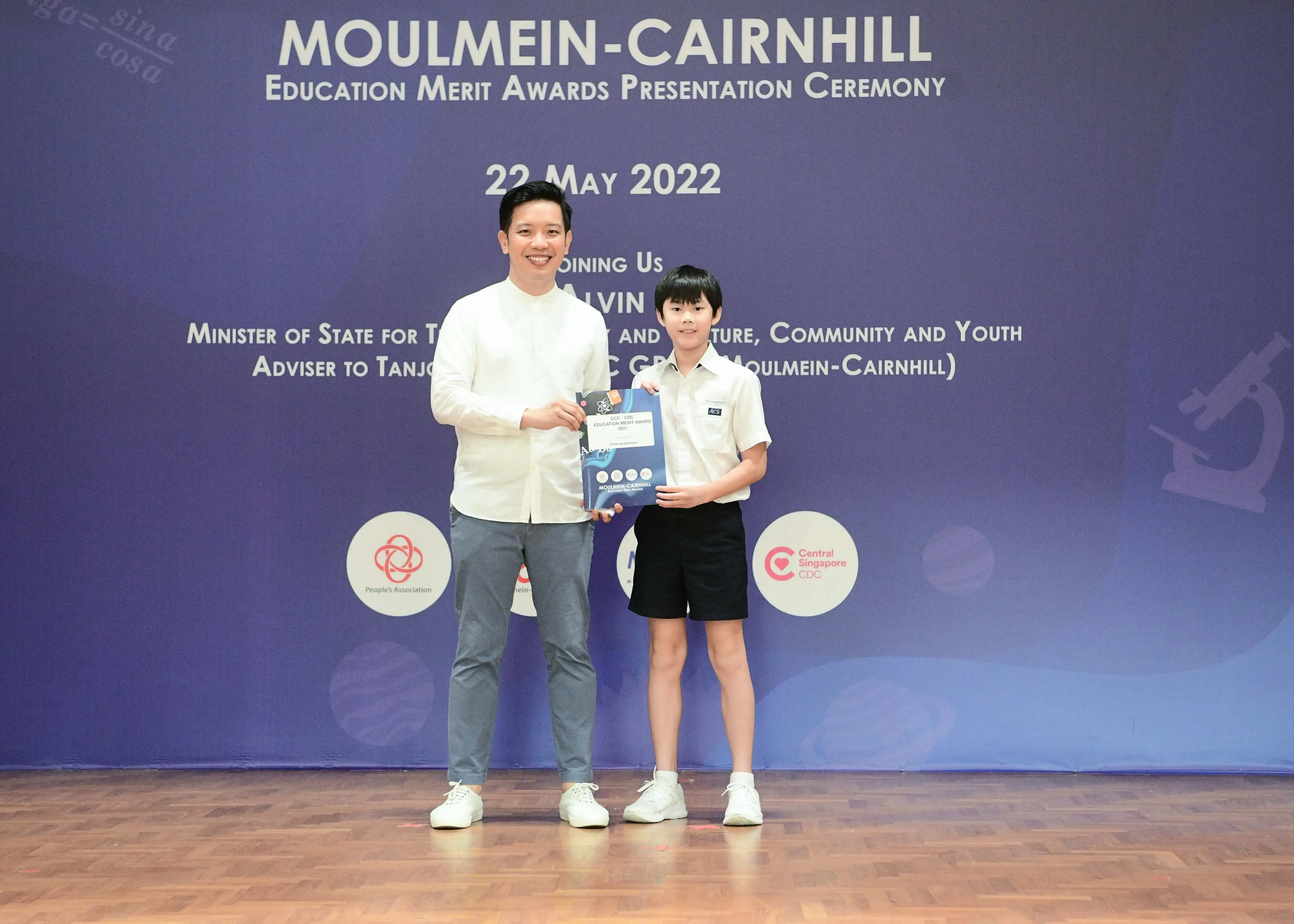 An adult and a young student hold an award certificate at the Moulmein-Cairnhill Education Merit Awards on 22 May 2022.
