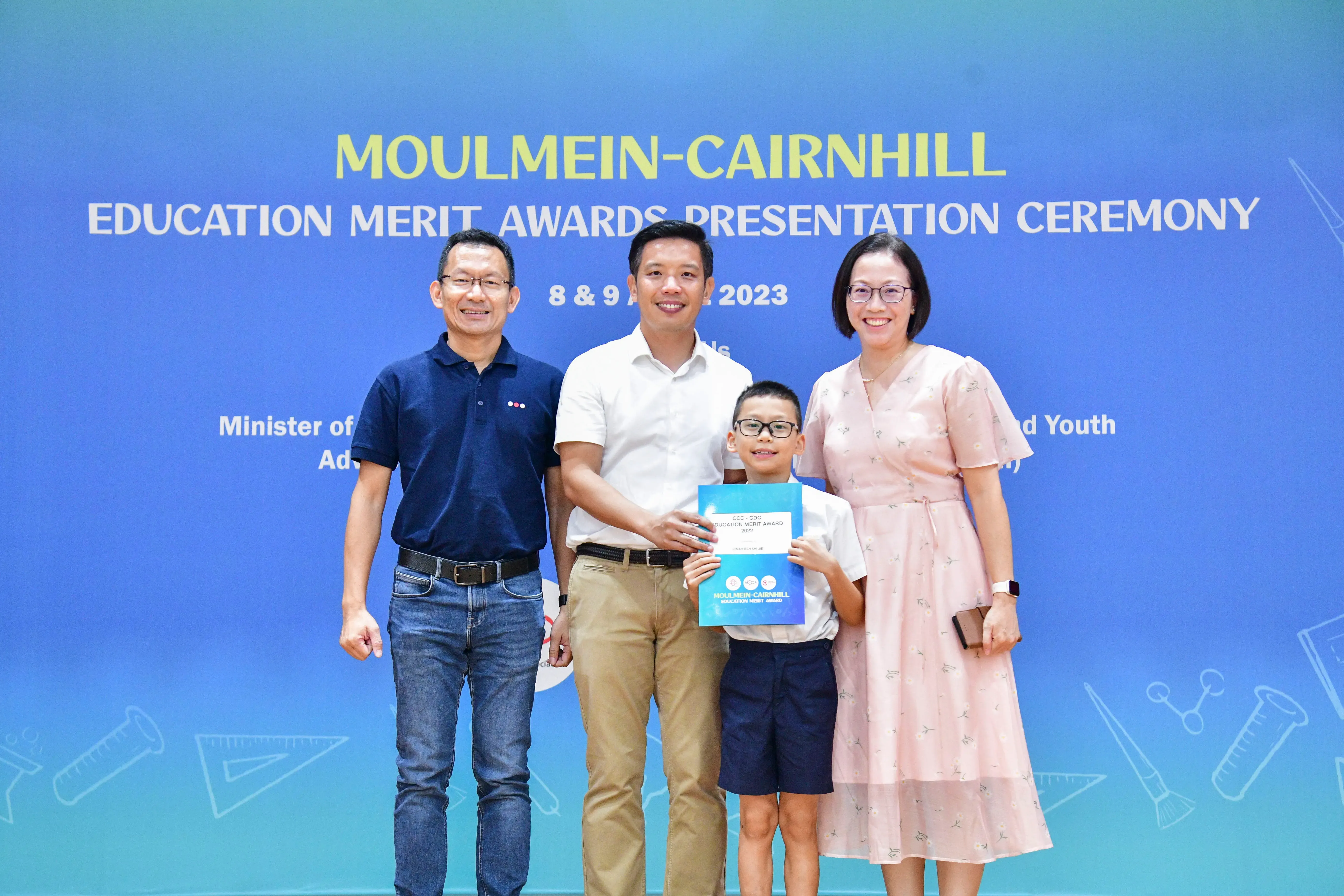 Three adults and a boy holding an award certificate pose at the Moulmein-Cairnhill Education Merit Awards 2023.