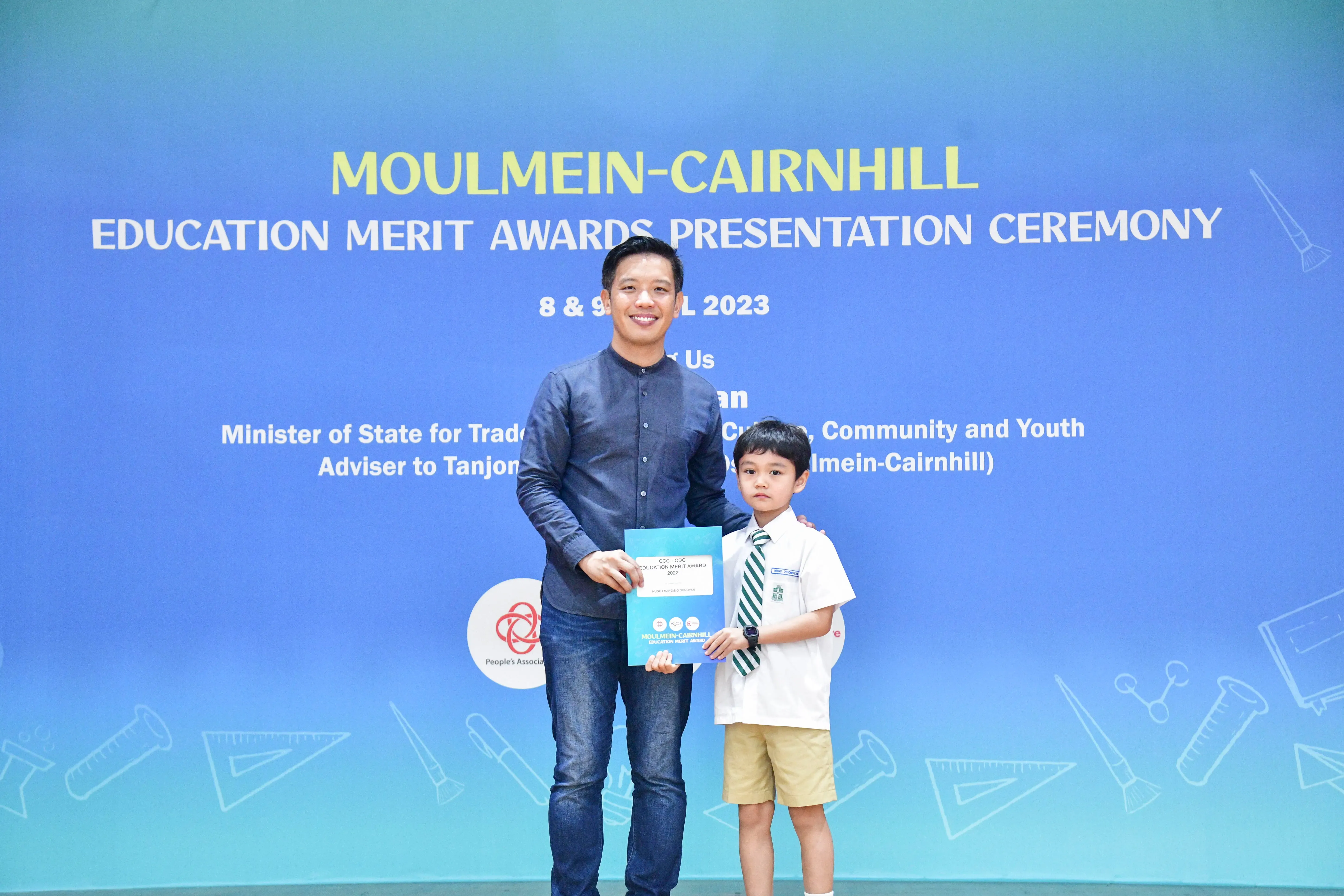 A man and a young boy in school uniform hold an award certificate at the Moulmein-Cairnhill Education Merit Awards 2023.