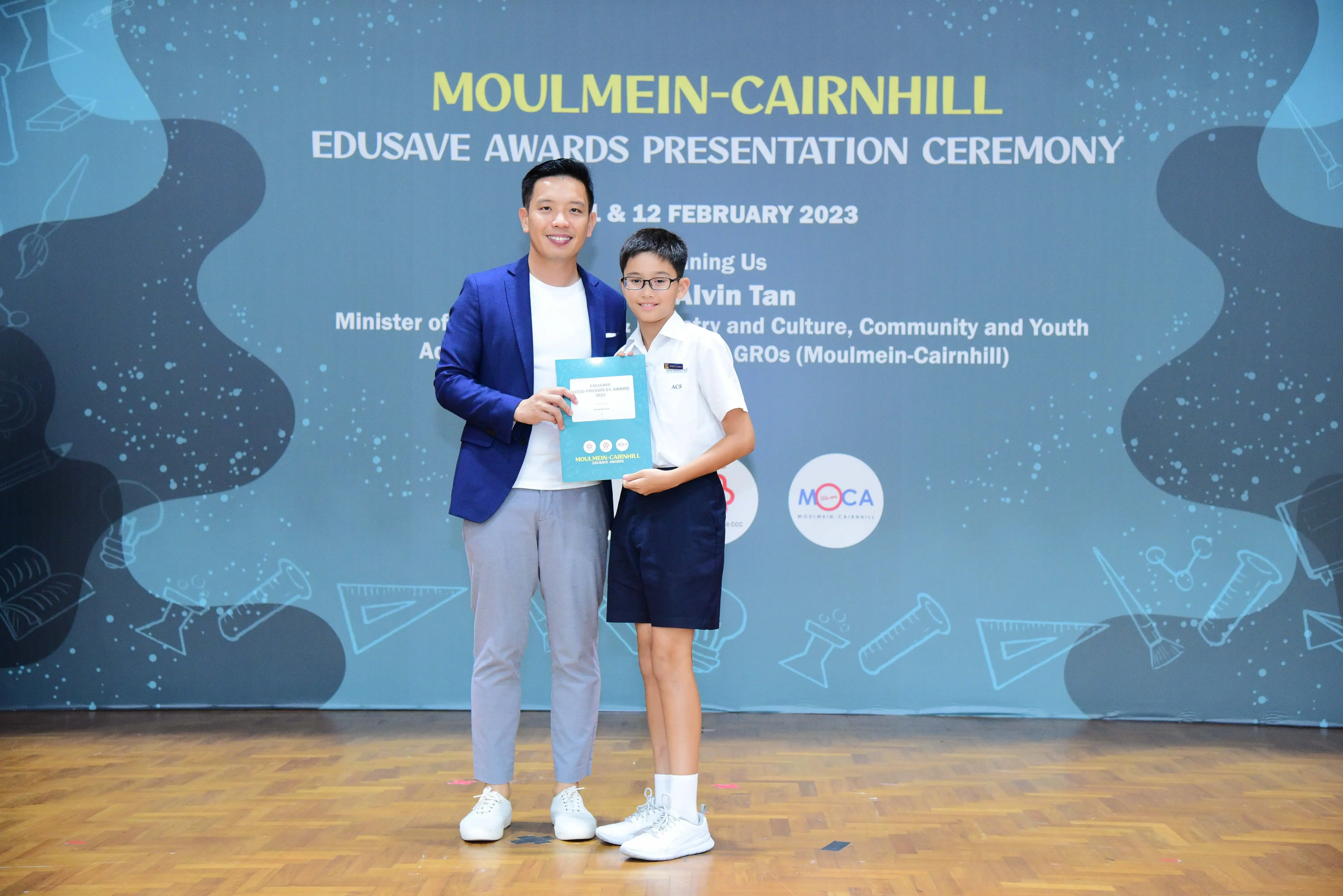 Man in blue blazer and young student holding an award at Moulmein-Cairnhill Edusave Awards Ceremony 2023.