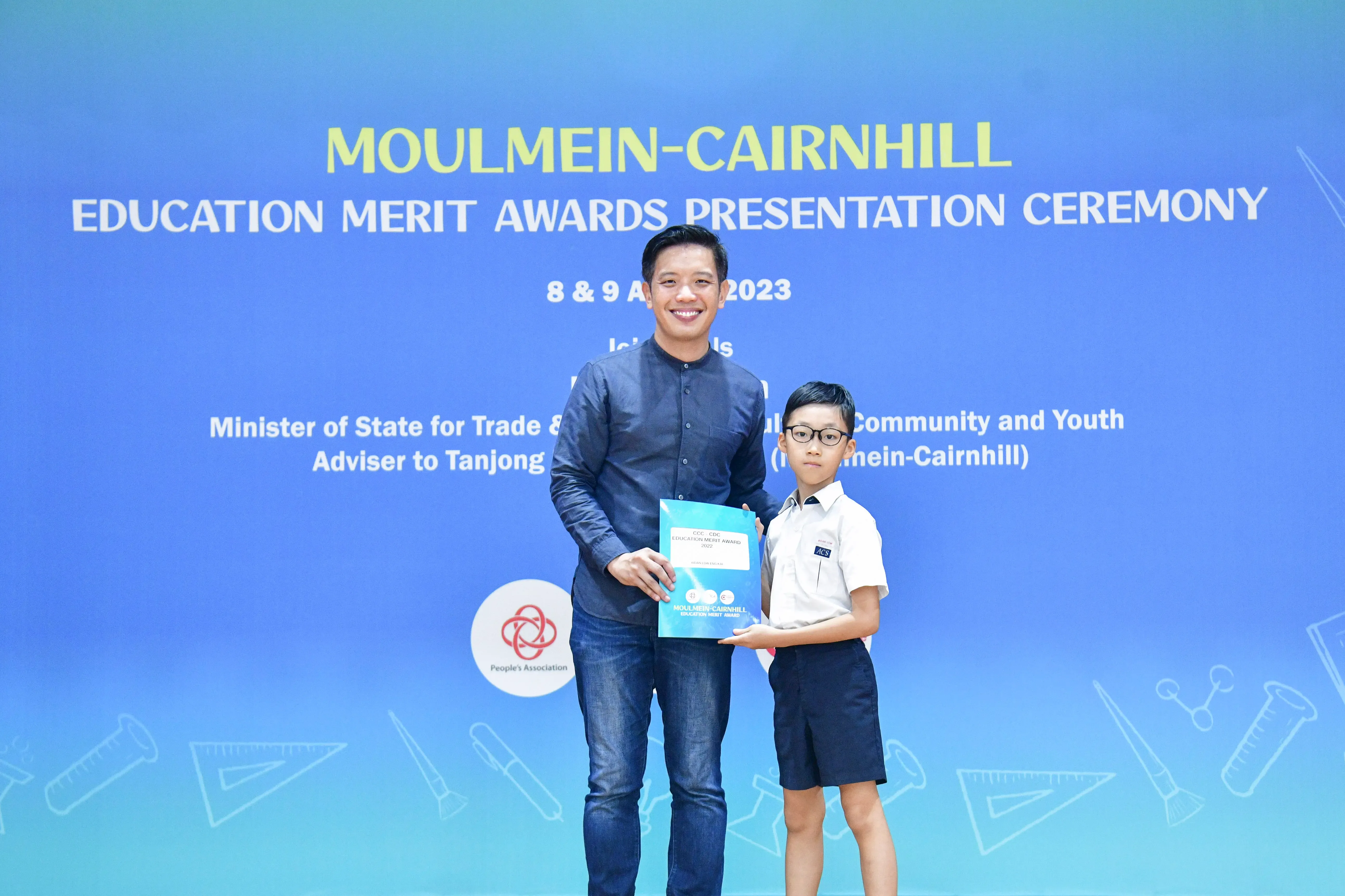 A man and a young boy hold an award certificate at the Moulmein-Cairnhill Education Merit Awards Ceremony 2023.