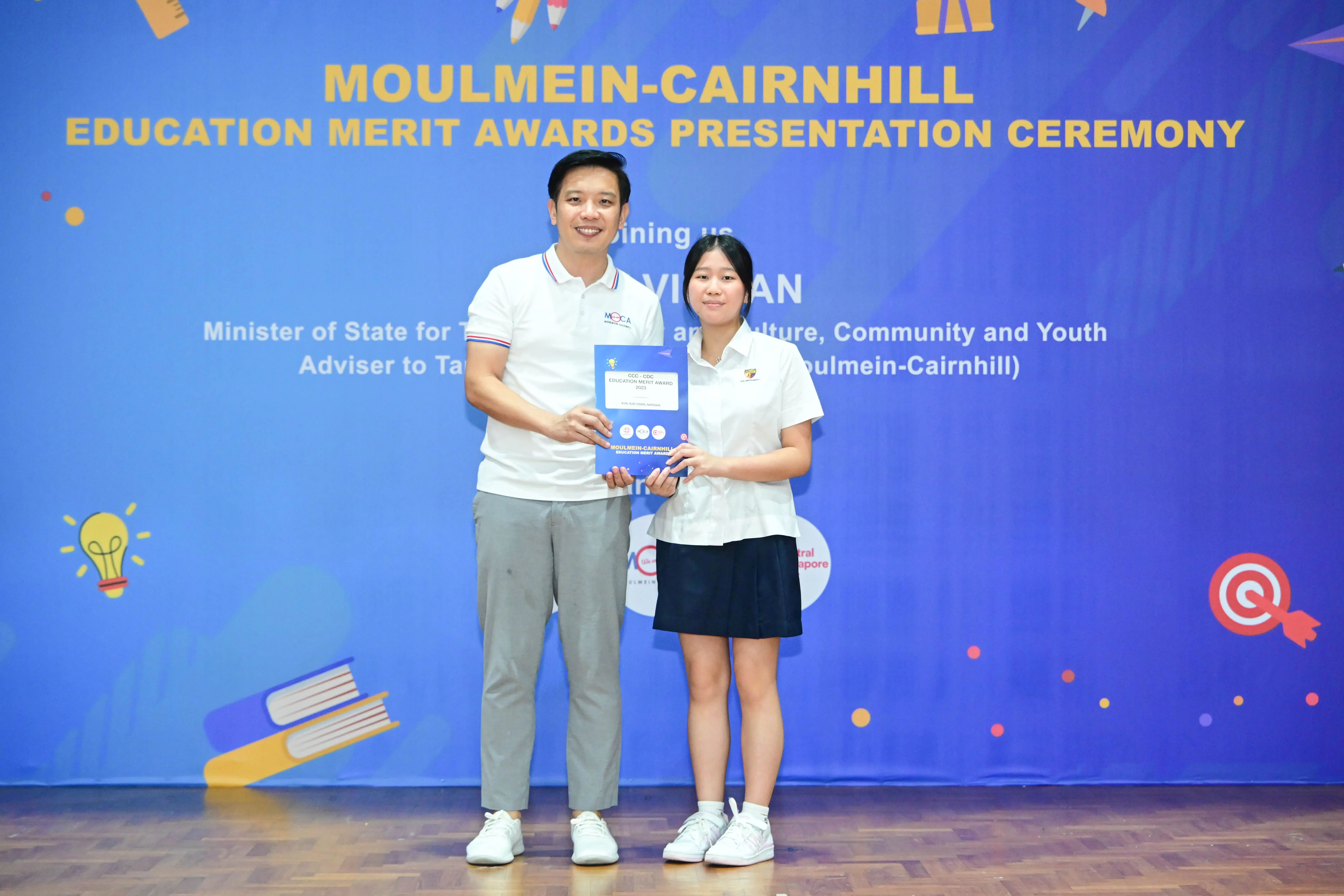 Two people hold a certificate at the Moulmein-Cairnhill Education Merit Awards Presentation Ceremony.