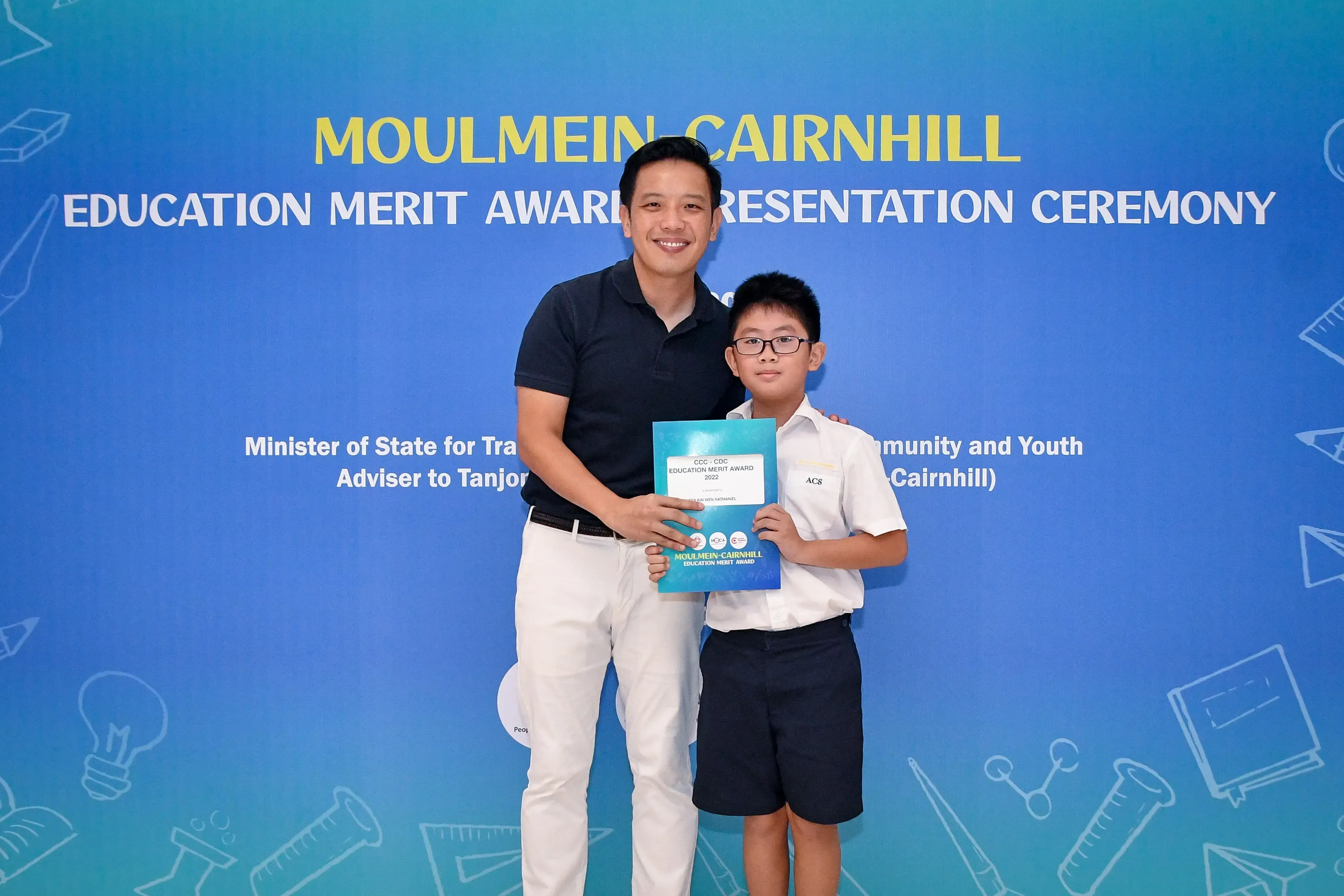 A man and a young boy holding a certificate pose at the Moulmein-Cairnhill Education Merit Award Ceremony.