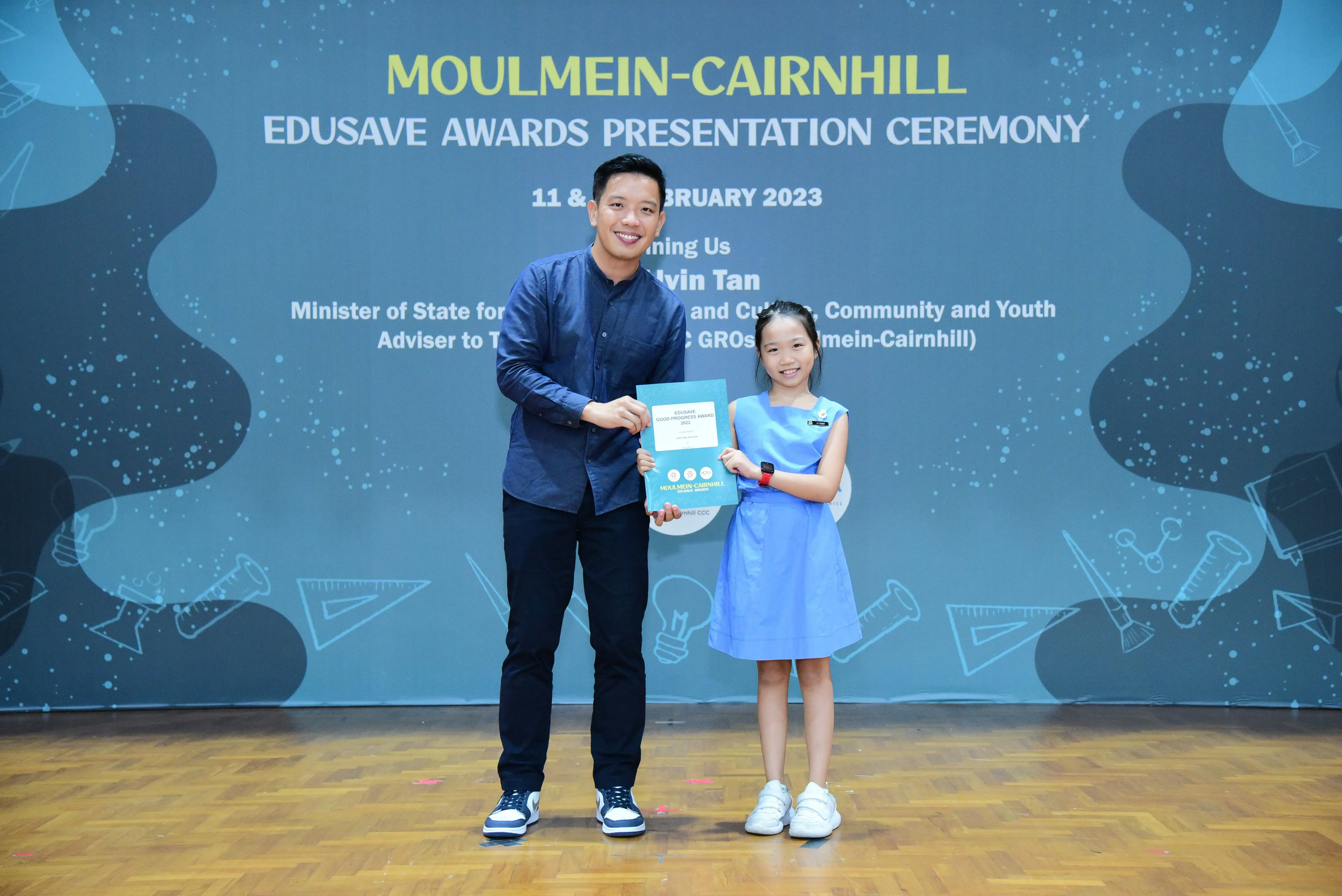 A man and a young girl hold a certificate at the Moulmein-Cairnhill Edusave Awards Ceremony in February 2023.