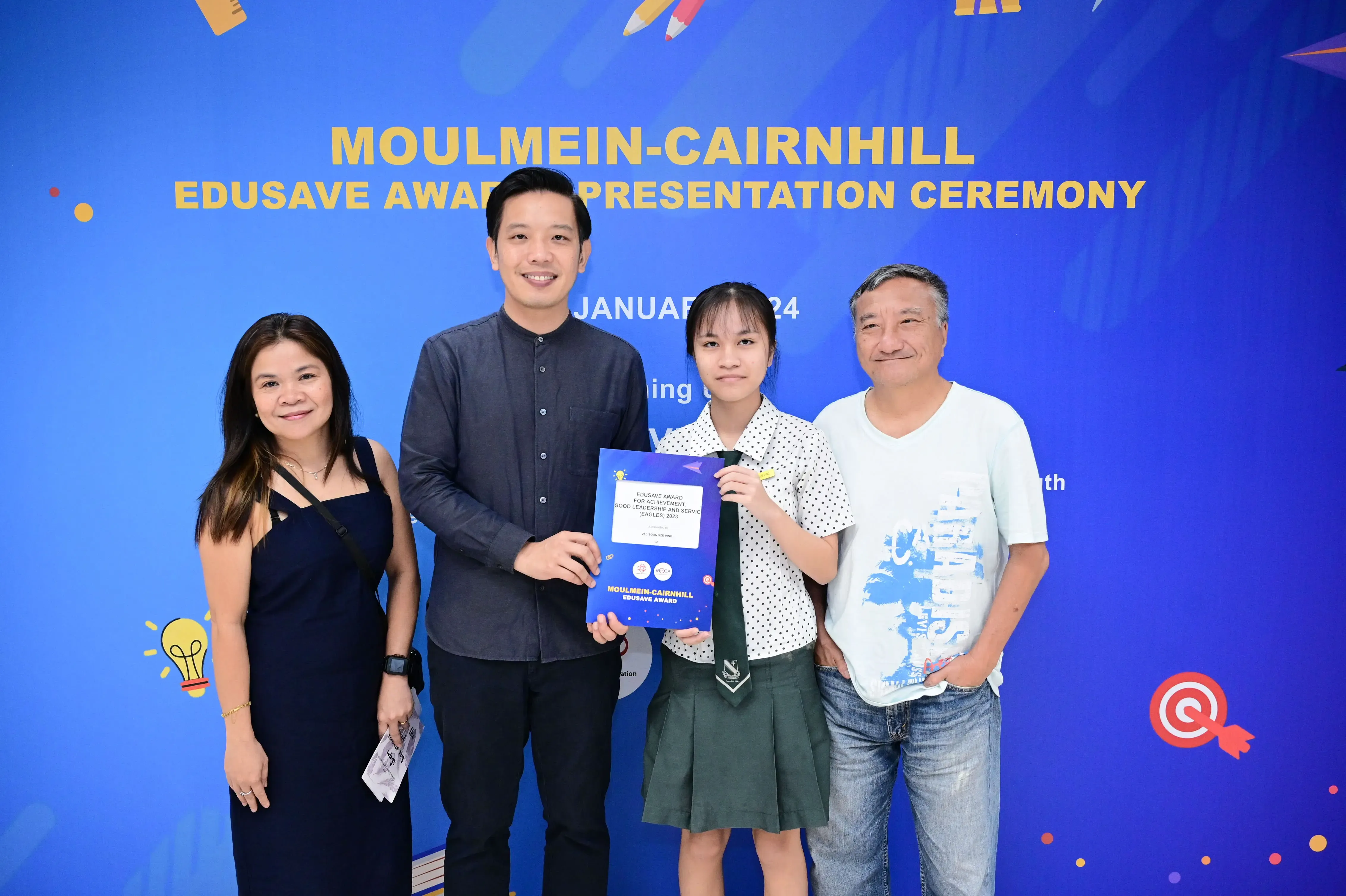 Four people pose together at the Moulmein-Cairnhill Edusave Award Presentation Ceremony, with a student holding a certificate.
