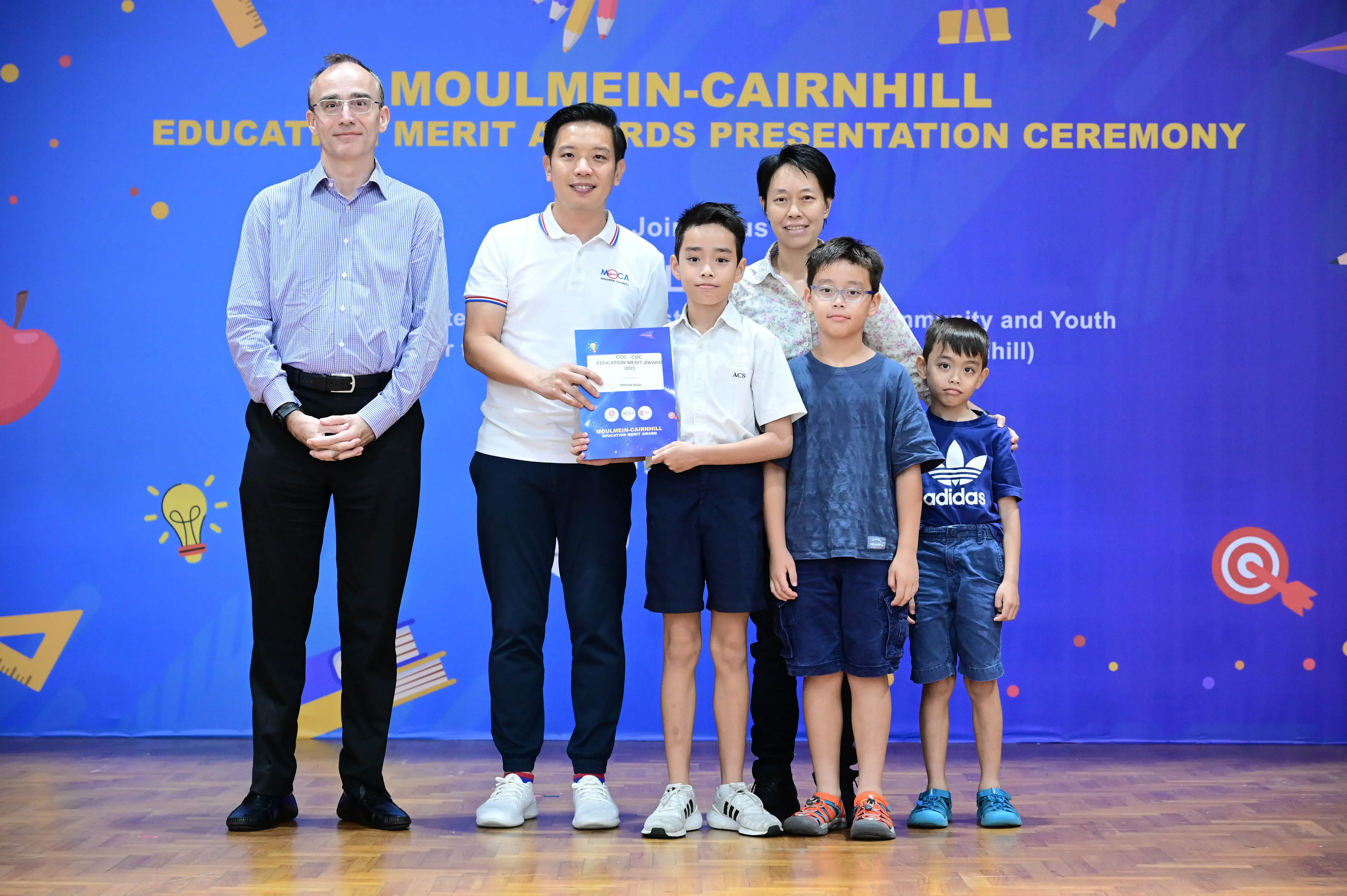 Group of adults and children posing at the Moulmein-Cairnhill Education Merit Awards Presentation Ceremony.