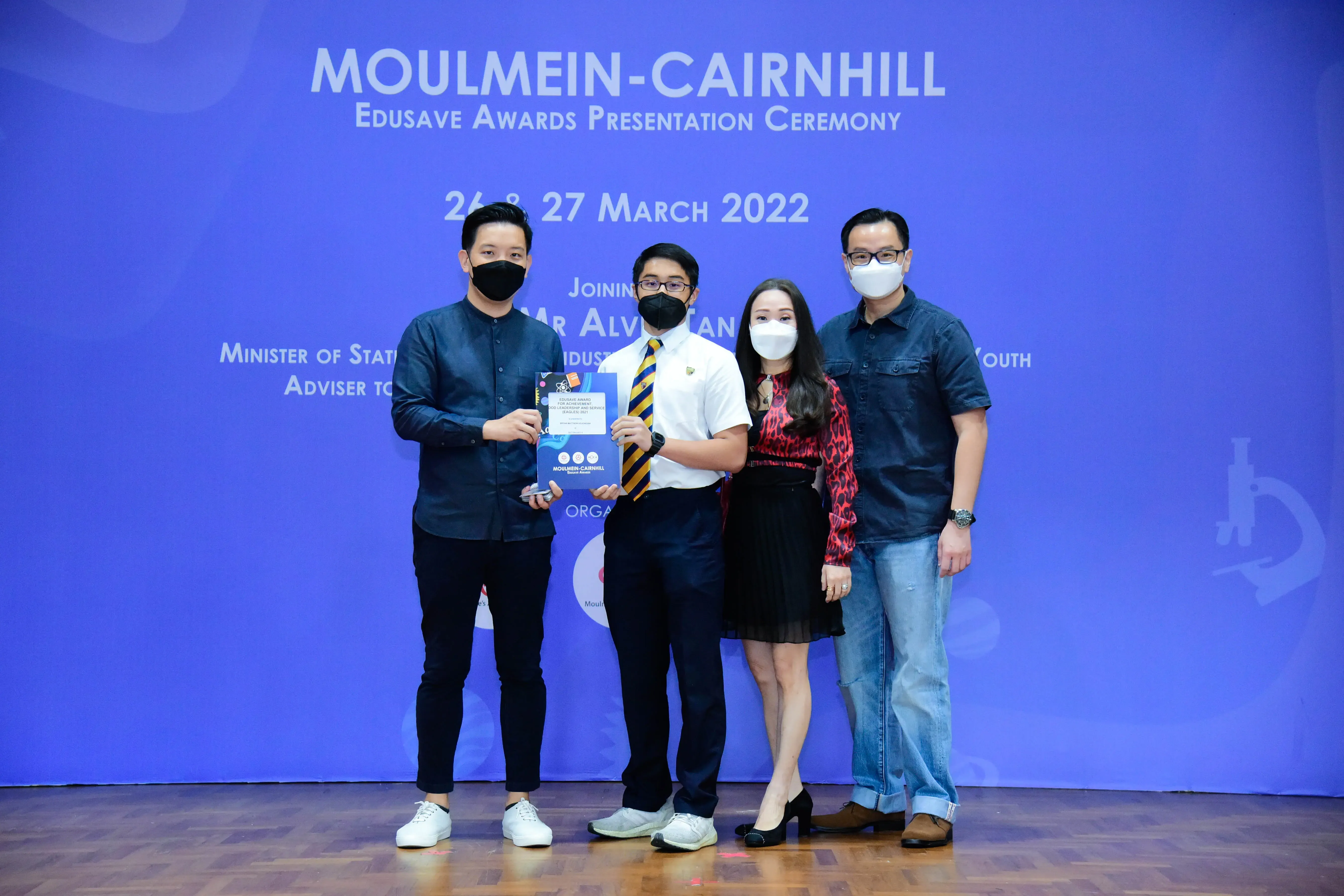 Four masked people pose at the Moulmein-Cairnhill Edusave Awards Presentation Ceremony on 27 March 2022.