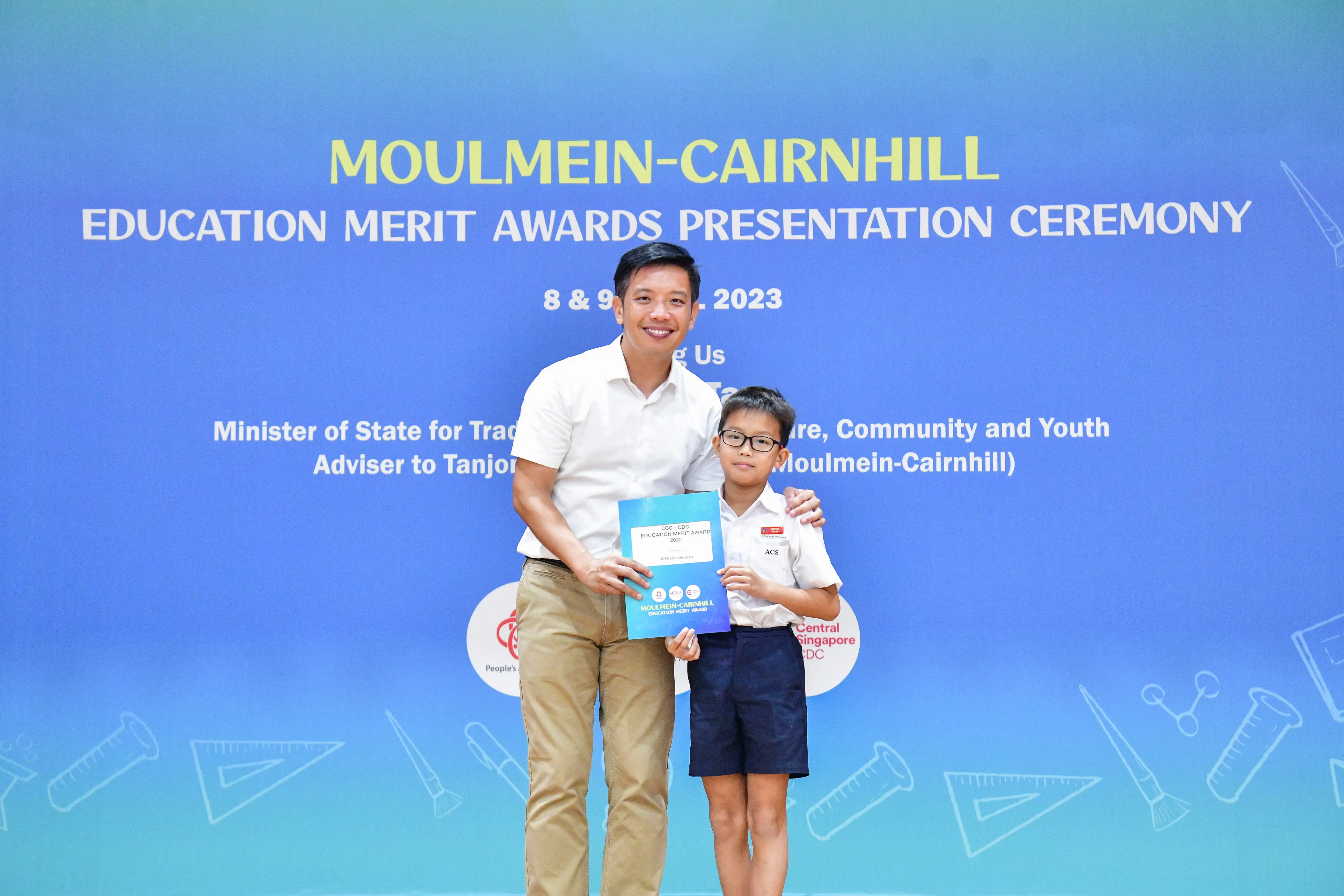 A man and a young boy pose together holding an award certificate at the Moulmein-Cairnhill Education Merit Awards 2023.