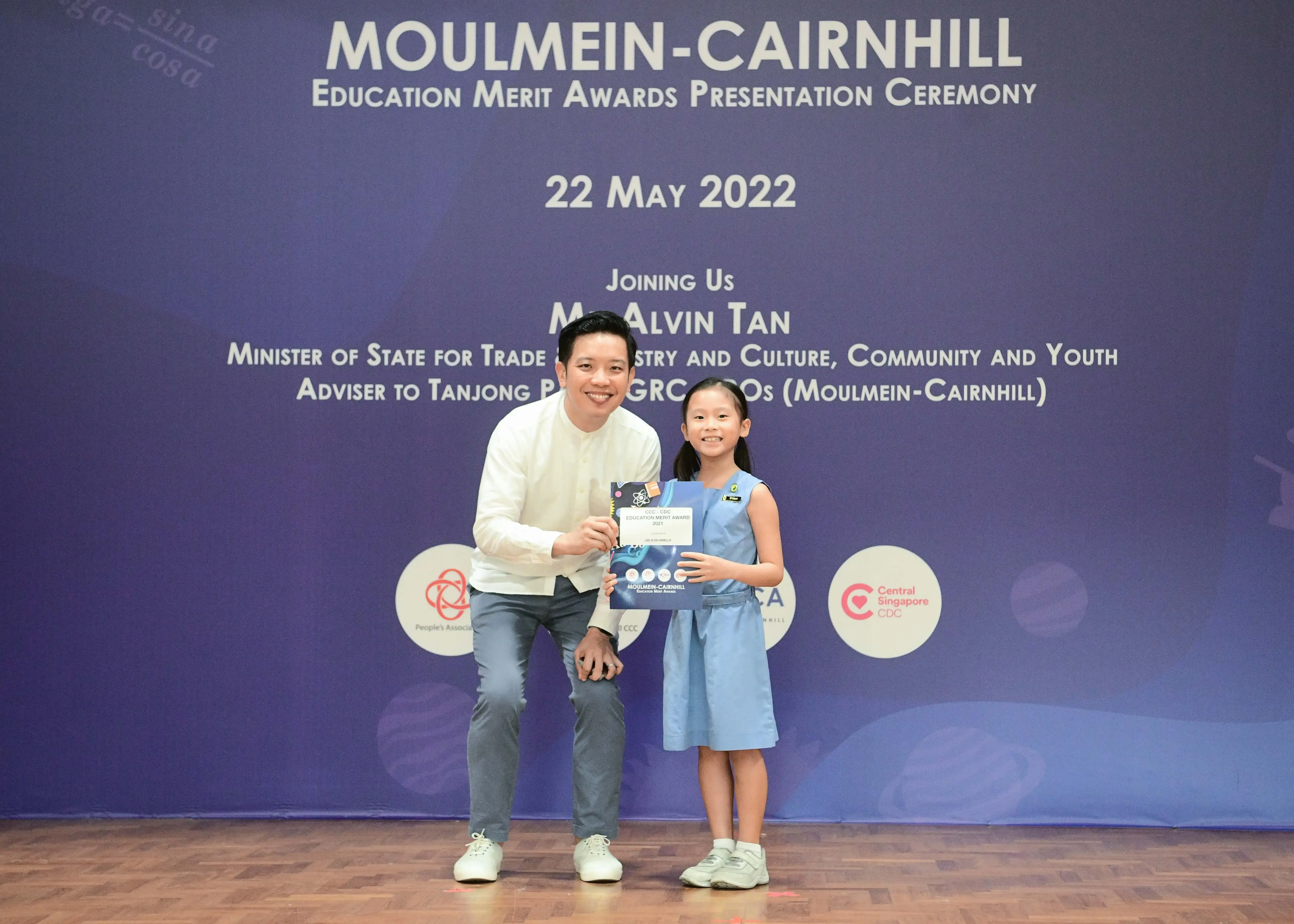 A man and a young girl pose holding an award at the Moulmein-Cairnhill Education Merit Awards Ceremony on 22 May 2022.