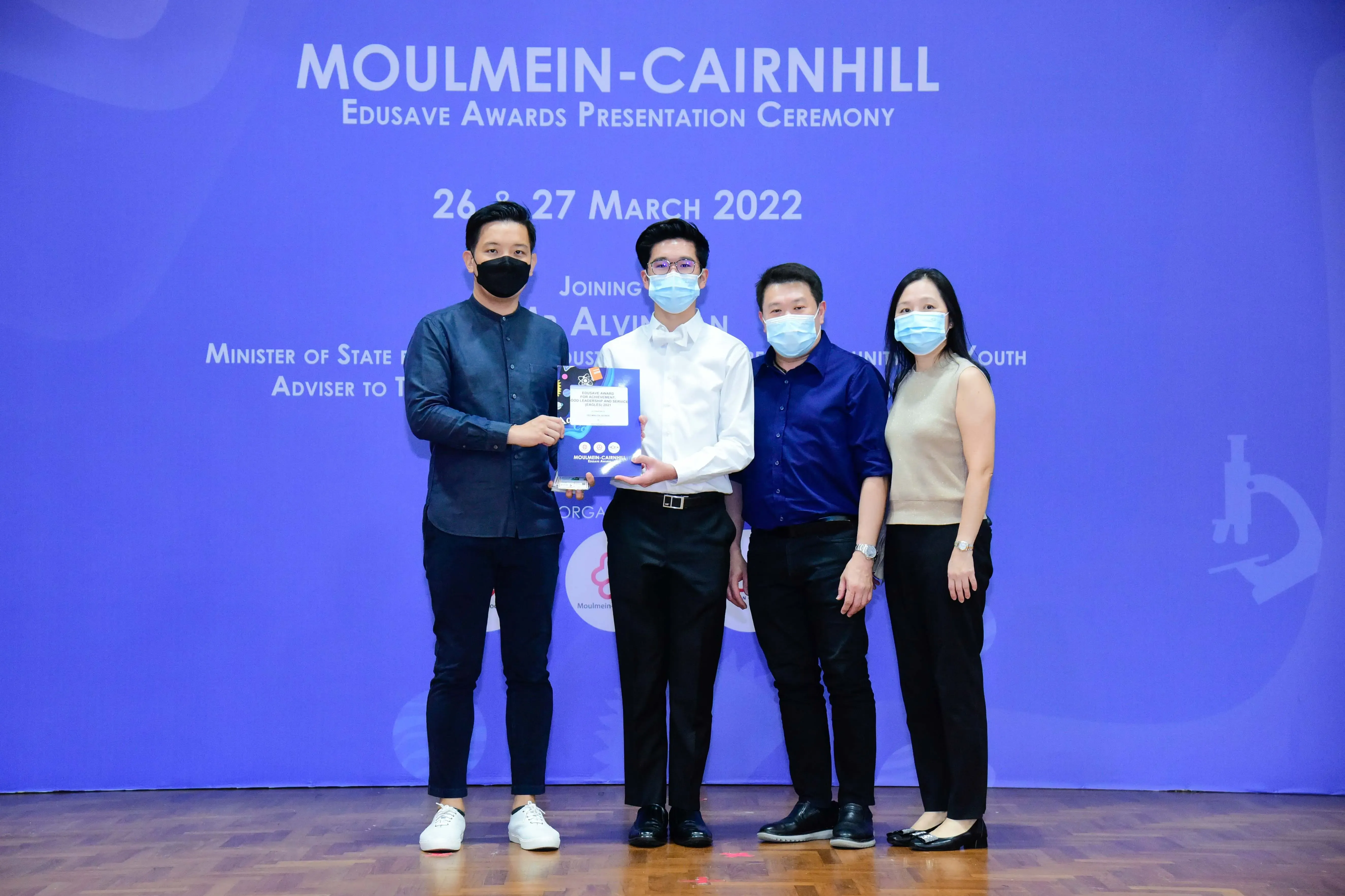 Four masked people pose at the Moulmein-Cairnhill Edusave Awards Presentation Ceremony on 26-27 March 2022.