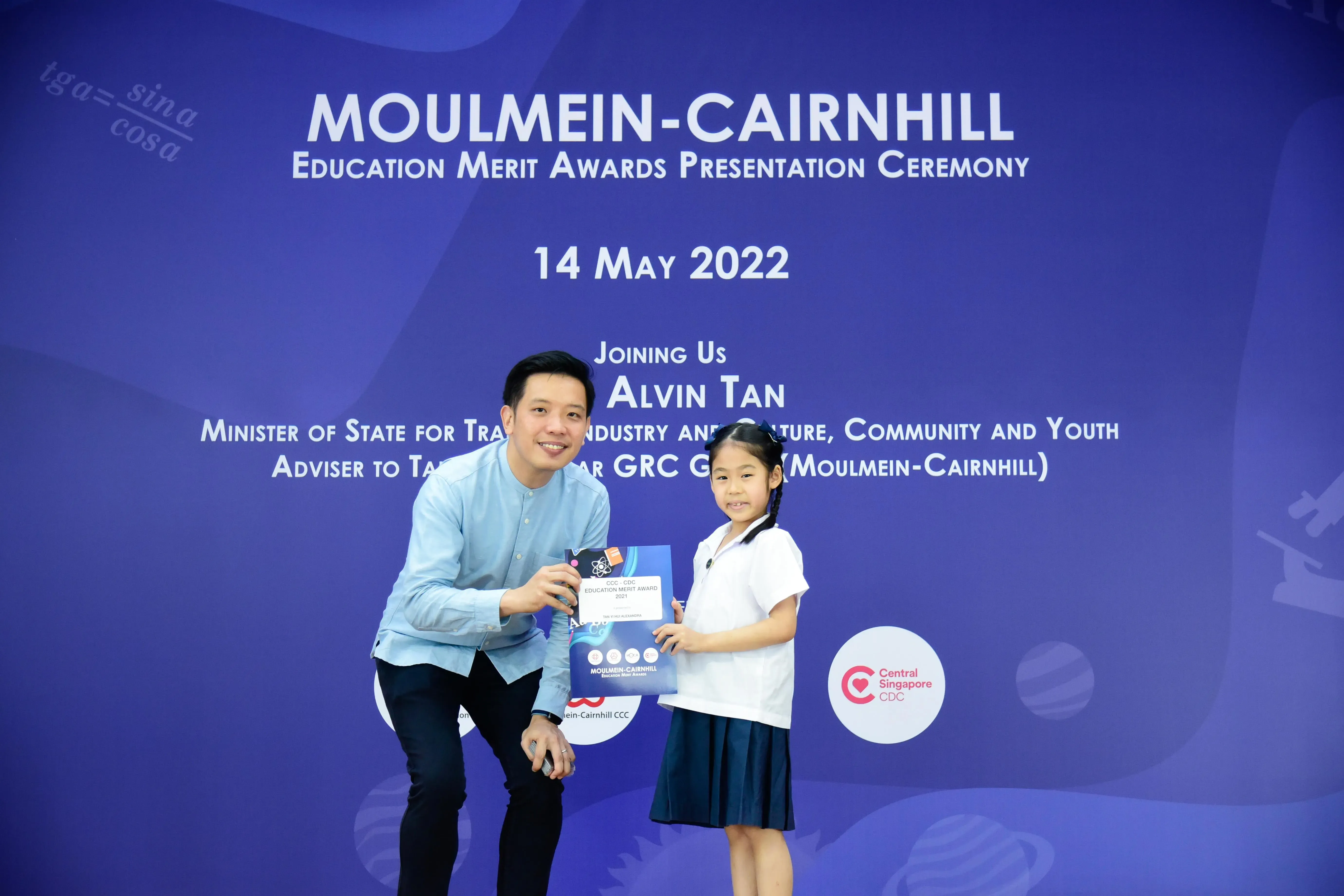 A man and a young girl hold an award certificate at the Moulmein-Cairnhill Education Merit Awards on 14 May 2022.