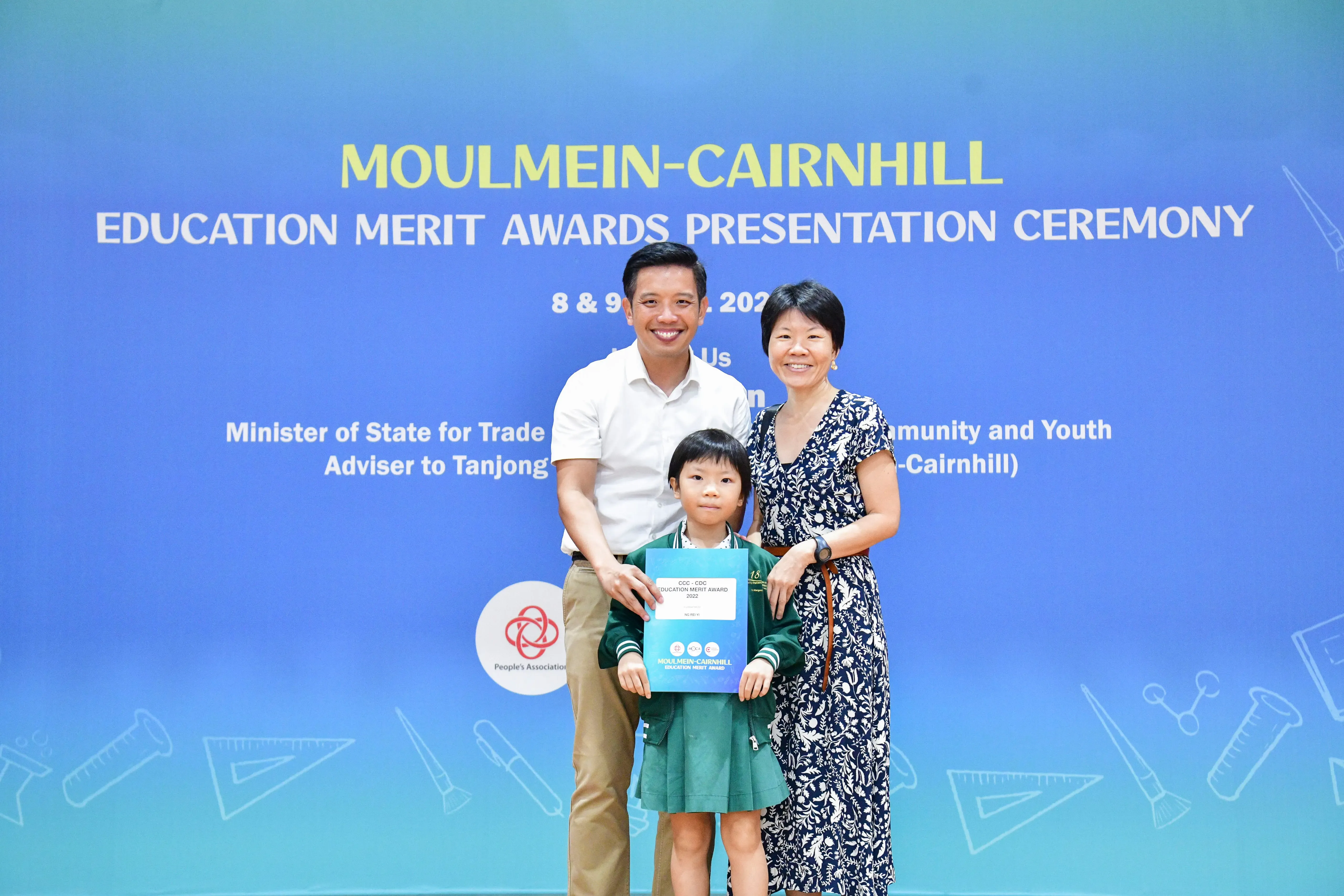 Two adults and a young girl in school uniform pose at the Moulmein-Cairnhill Education Merit Awards Ceremony.