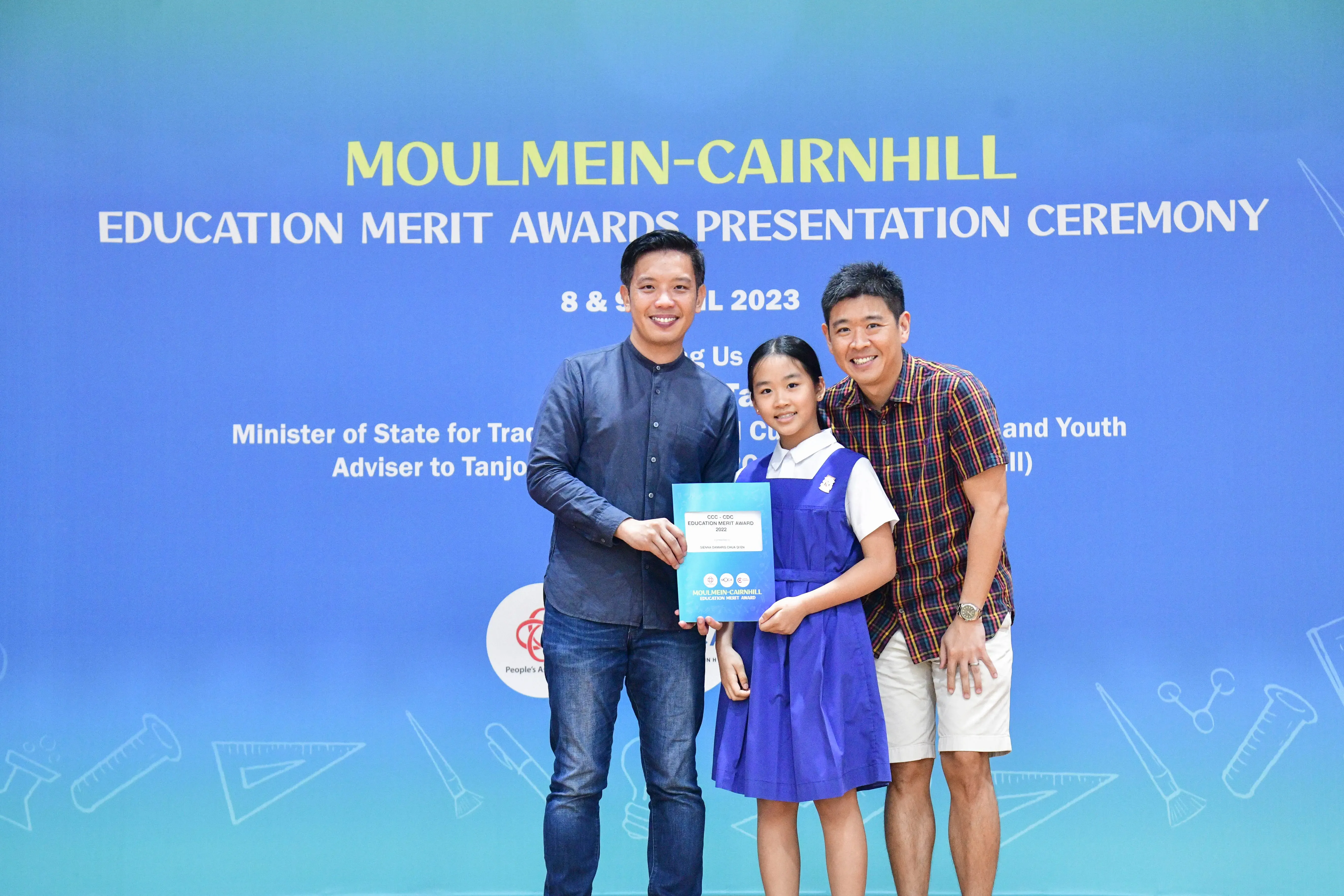 Two men and a girl in school uniform hold an award certificate at the Moulmein-Cairnhill Education Merit Awards 2023.