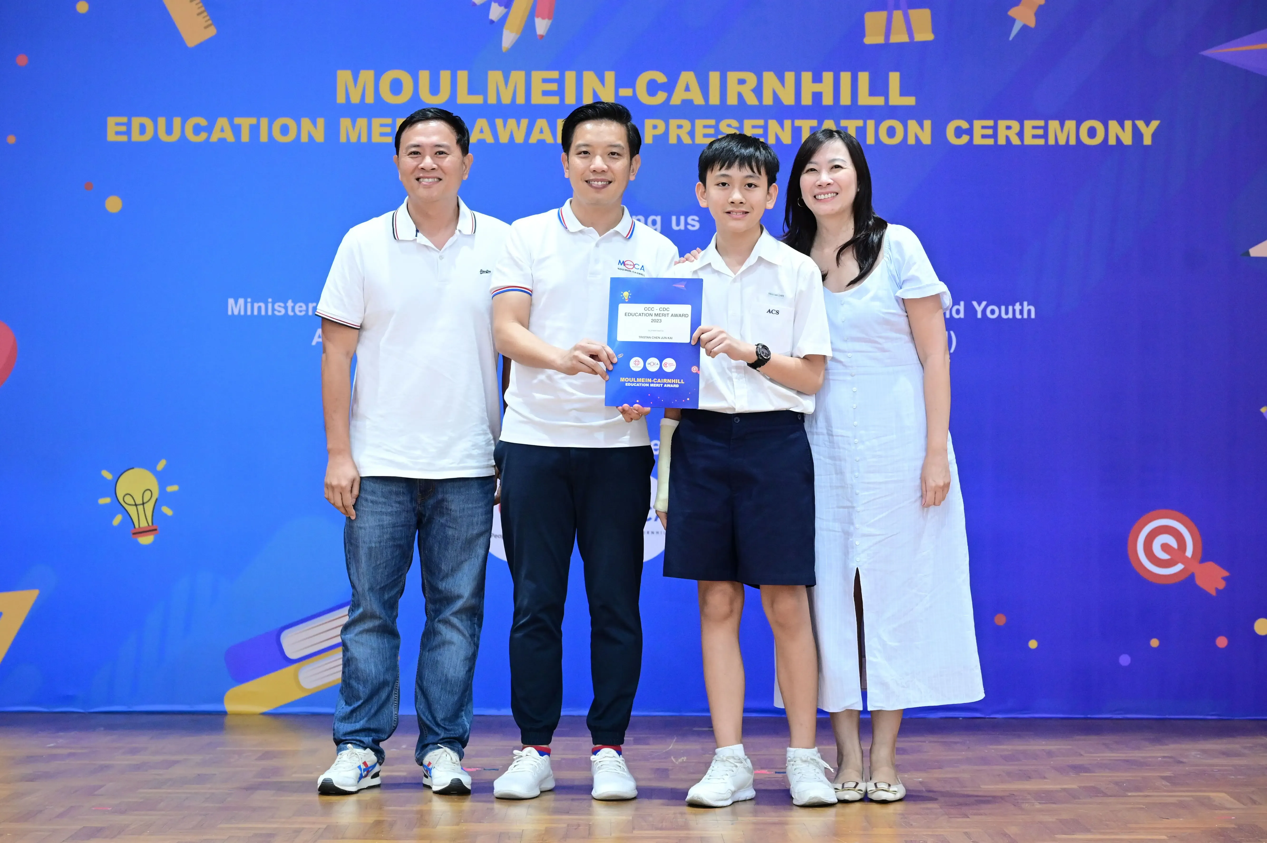 Four people pose holding a certificate at the Moulmein-Cairnhill Education Merit Award Presentation Ceremony.