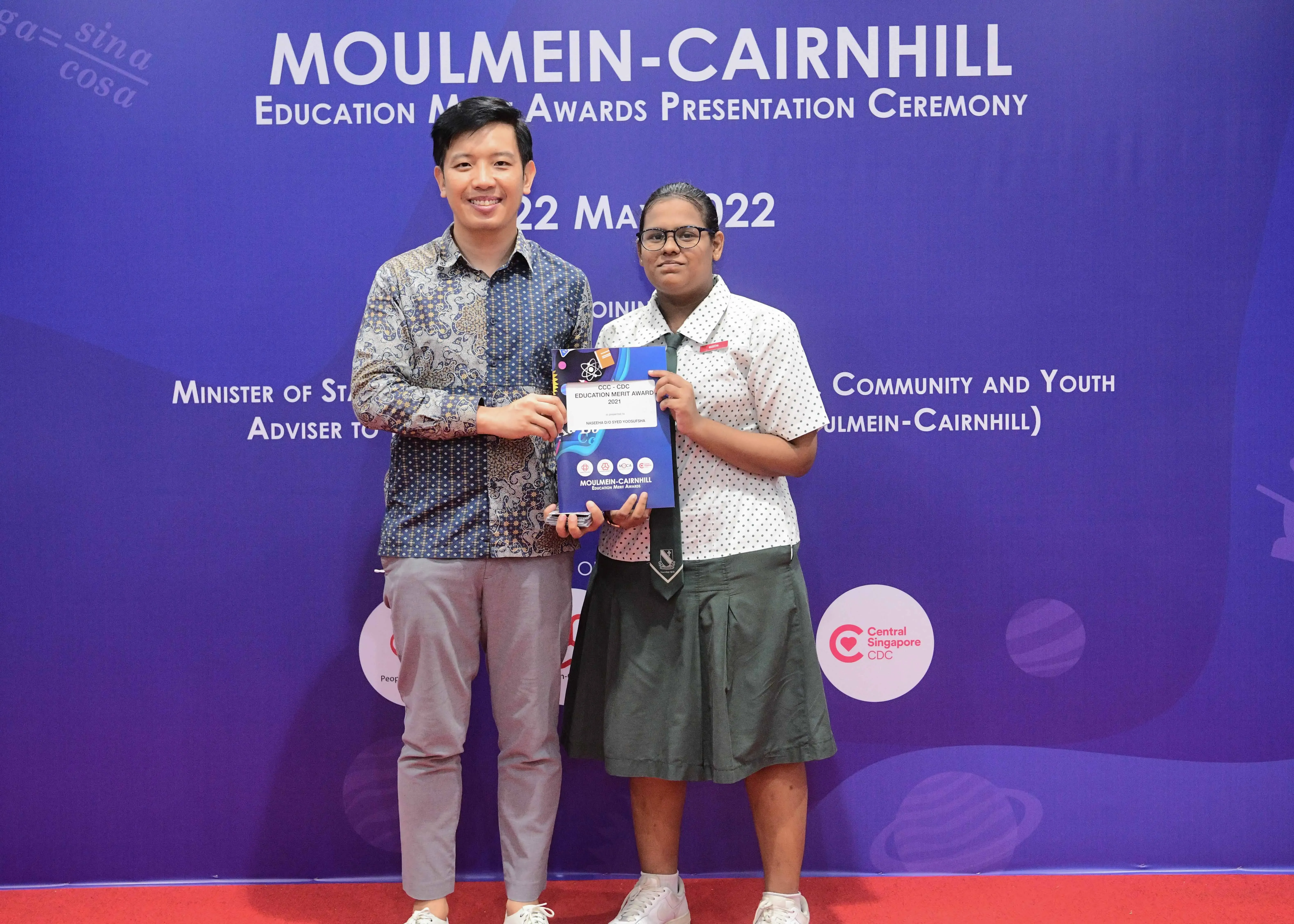 Two people hold an award certificate at the Moulmein-Cairnhill Education Merit Awards Presentation Ceremony, May 22, 2022.