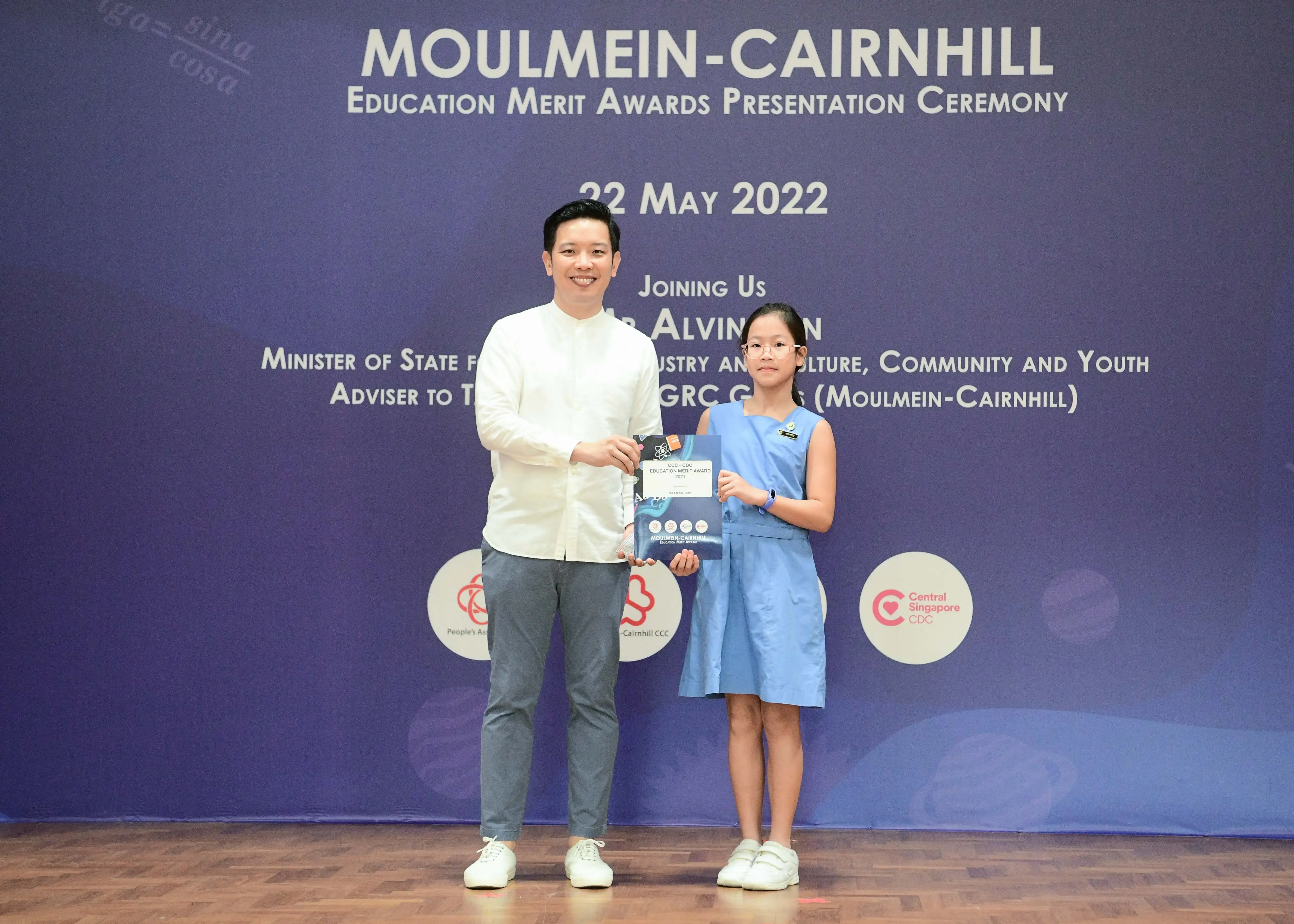 A man and a young girl hold an award together at the Moulmein-Cairnhill Education Merit Awards ceremony on 22 May 2022.