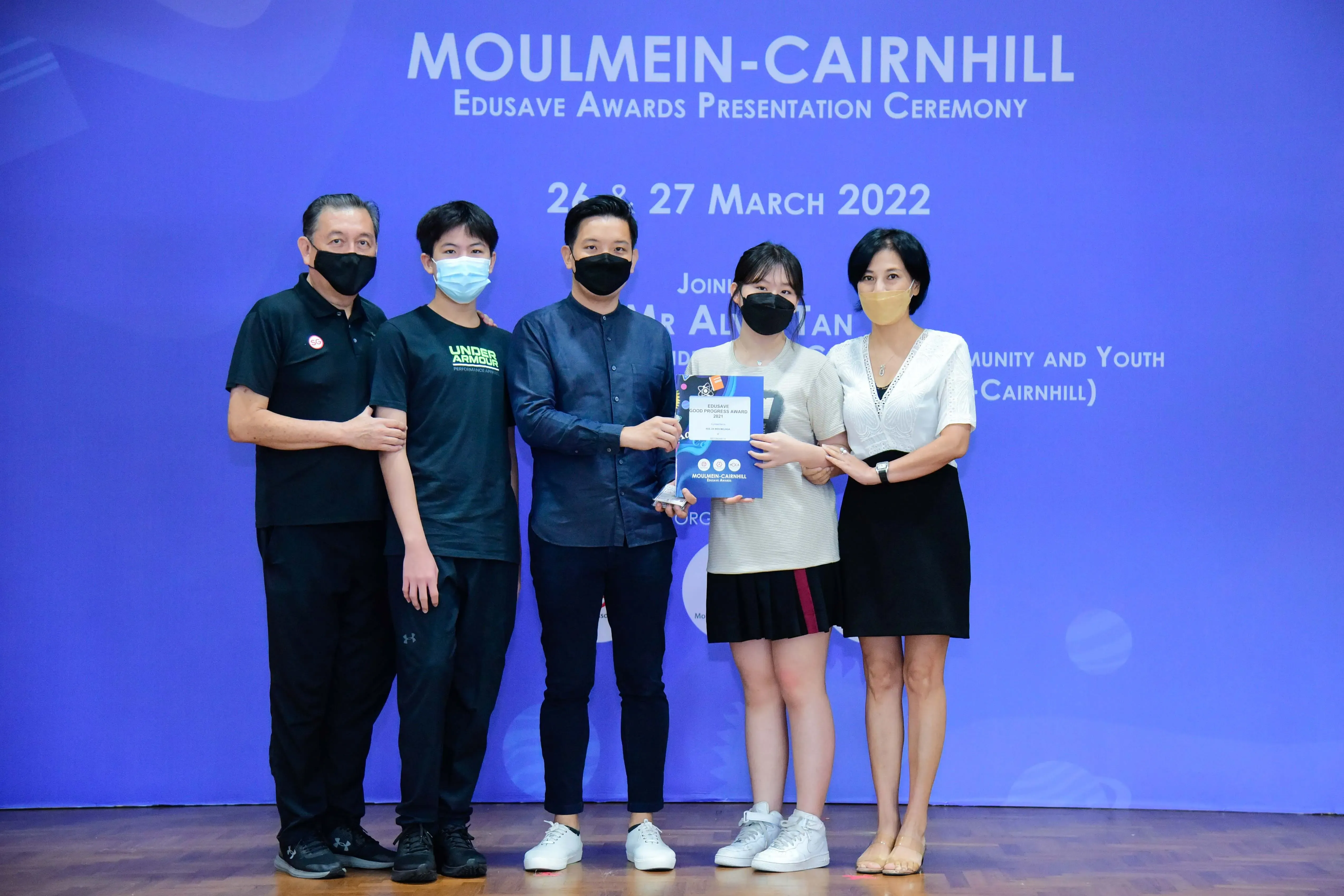 Five masked people pose at the Moulmein-Cairnhill Edusave Awards Presentation Ceremony on March 26-27, 2022.