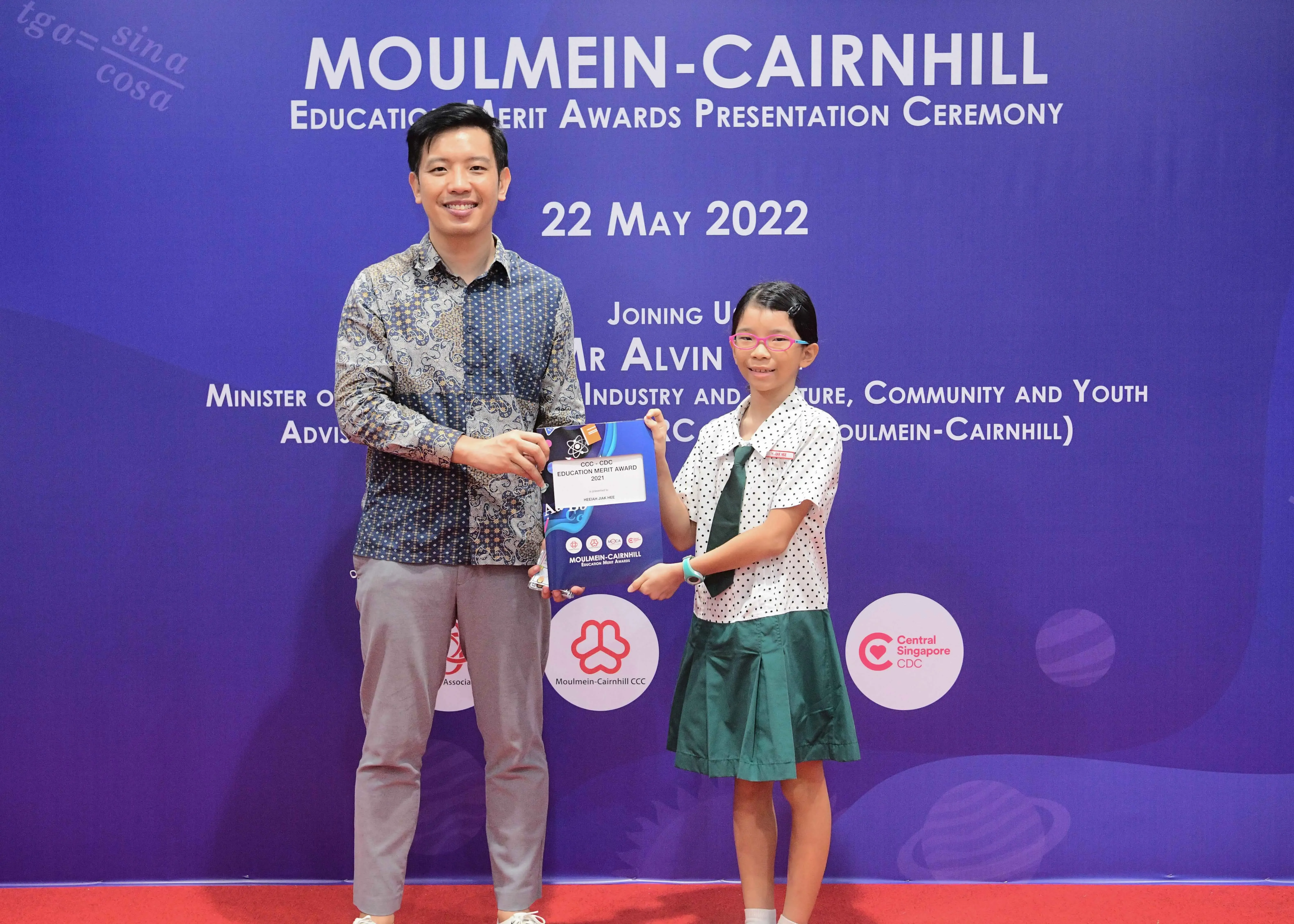A man and a young girl in school uniform hold an award certificate at the Moulmein-Cairnhill Education Merit Awards ceremony on 22 May 2022.
