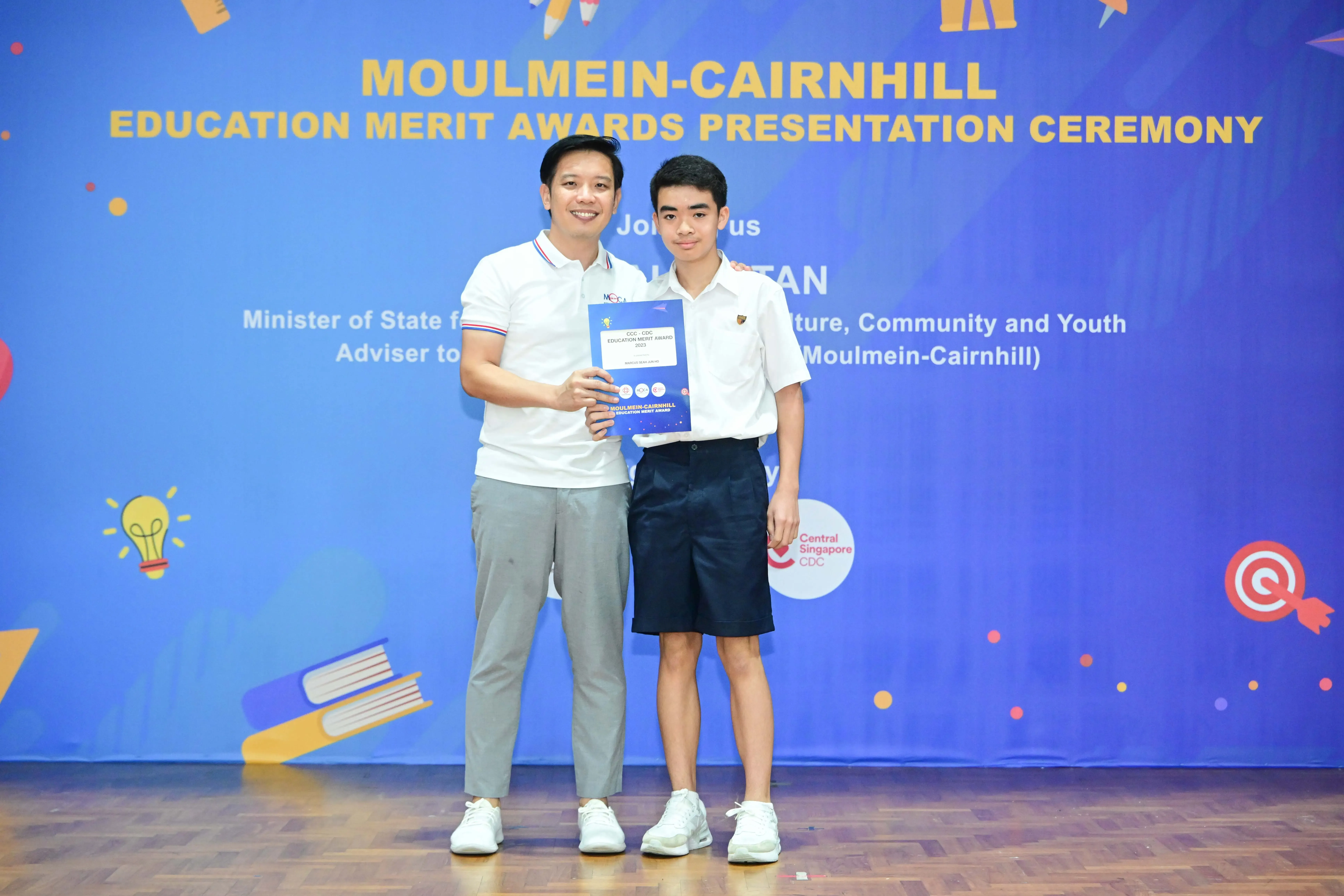 Two people pose holding an award certificate at the Moulmein-Cairnhill Education Merit Awards Presentation Ceremony.