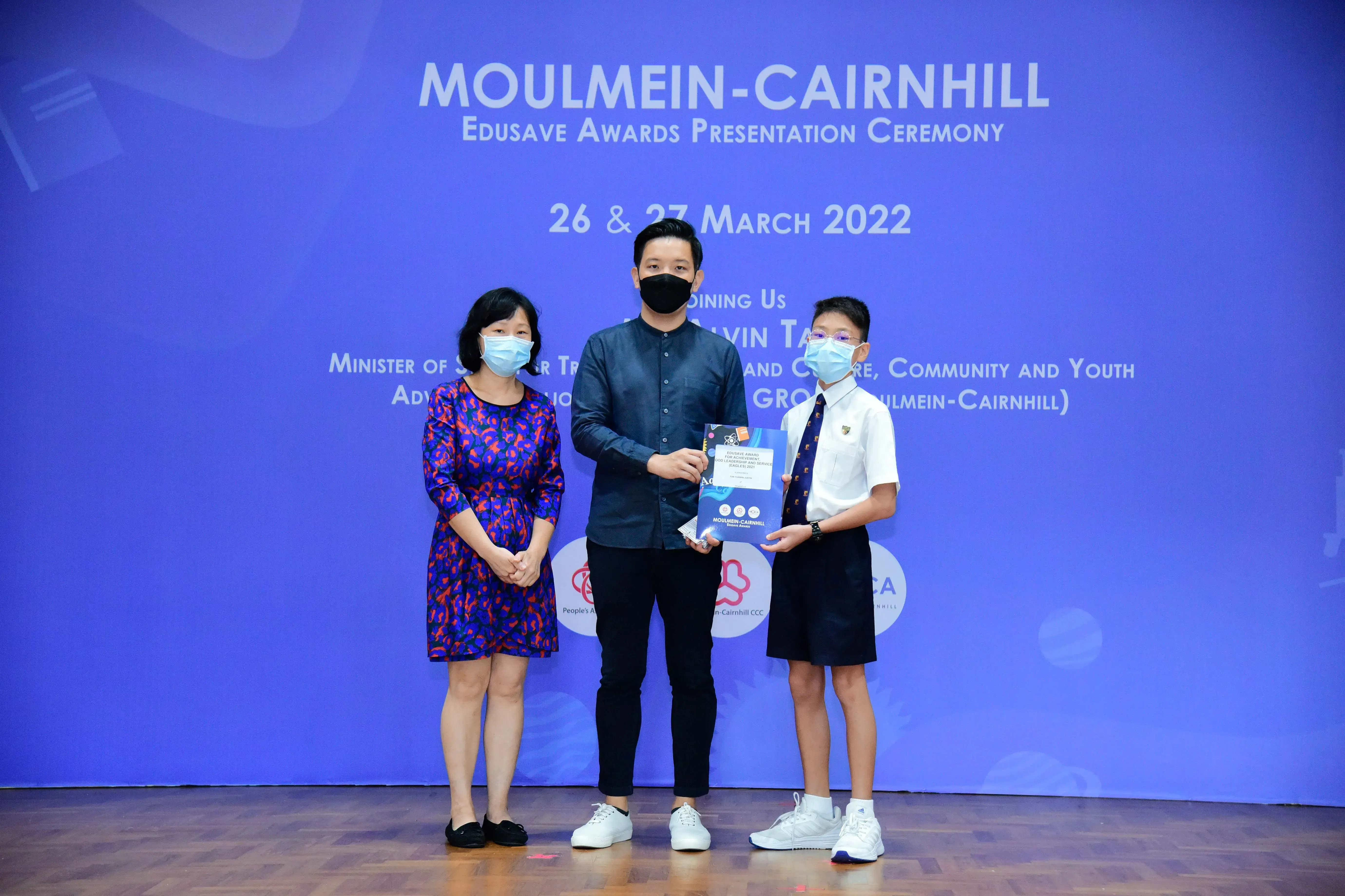 Three masked people pose at the Moulmein-Cairnhill Edusave Awards Presentation Ceremony on 26-27 March 2022.