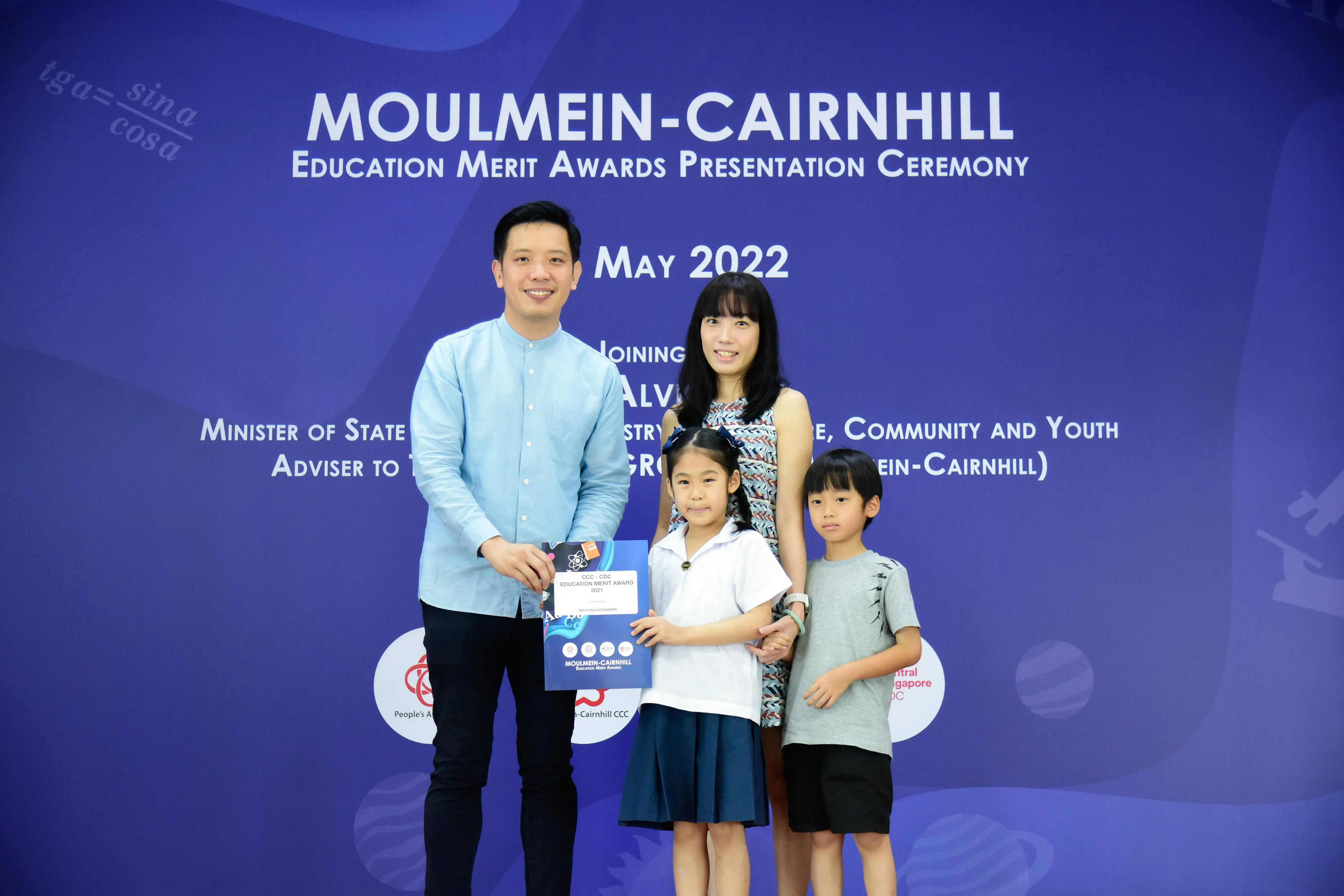 Two adults and two children pose at the Moulmein-Cairnhill Education Merit Awards Presentation Ceremony, May 2022.