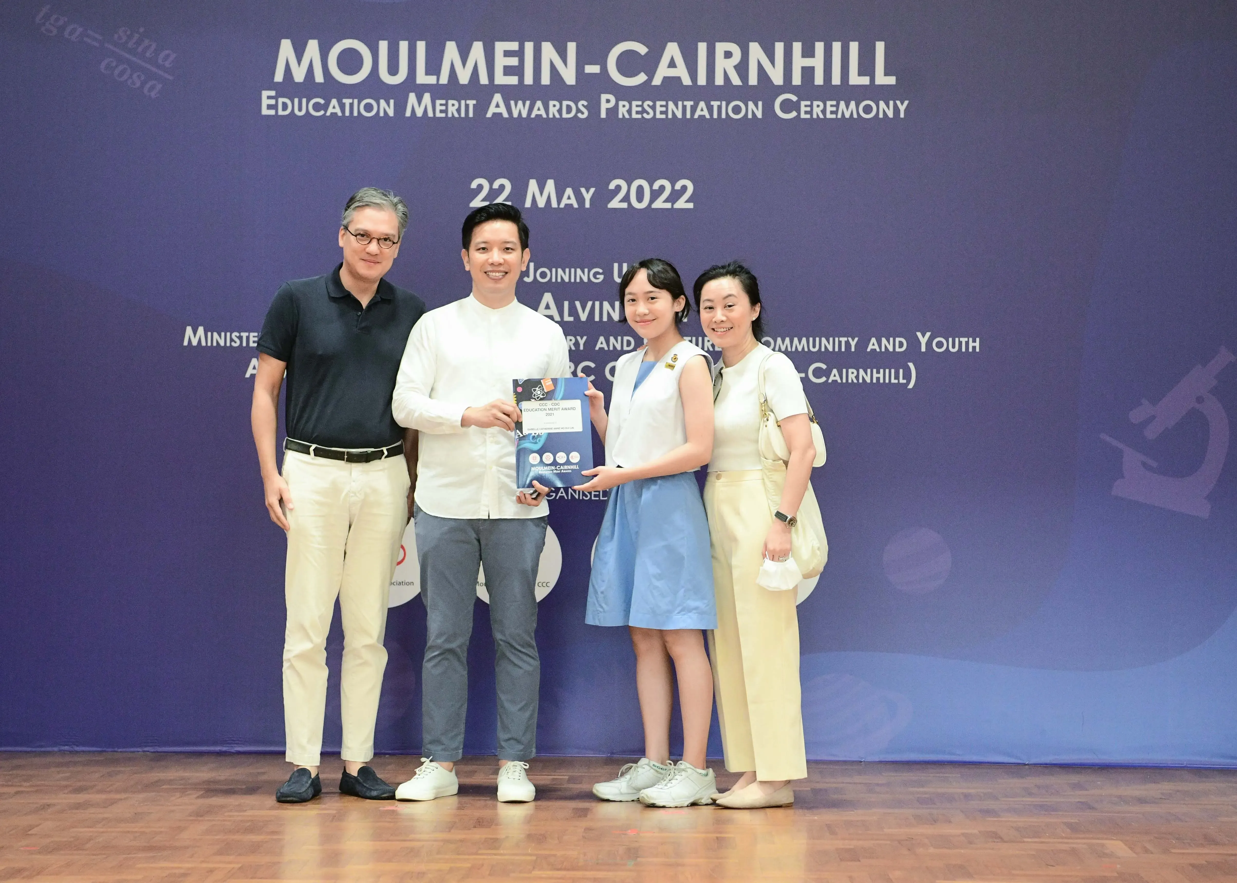 Four people pose together holding an award booklet at the Moulmein-Cairnhill Education Merit Awards Ceremony on 22 May 2022.