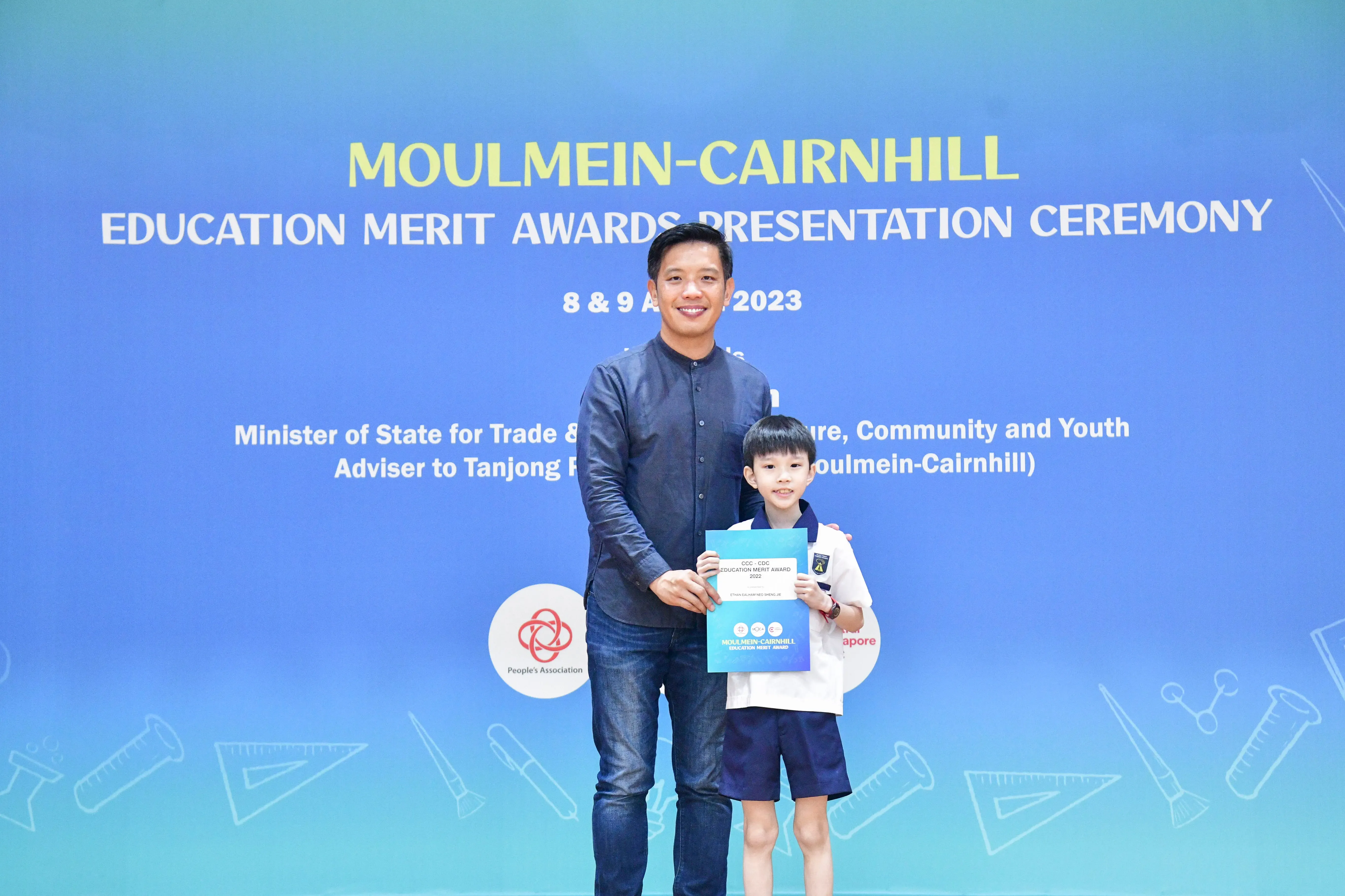 A man and a young boy pose together holding an award certificate at the Moulmein-Cairnhill Education Merit Awards 2023.
