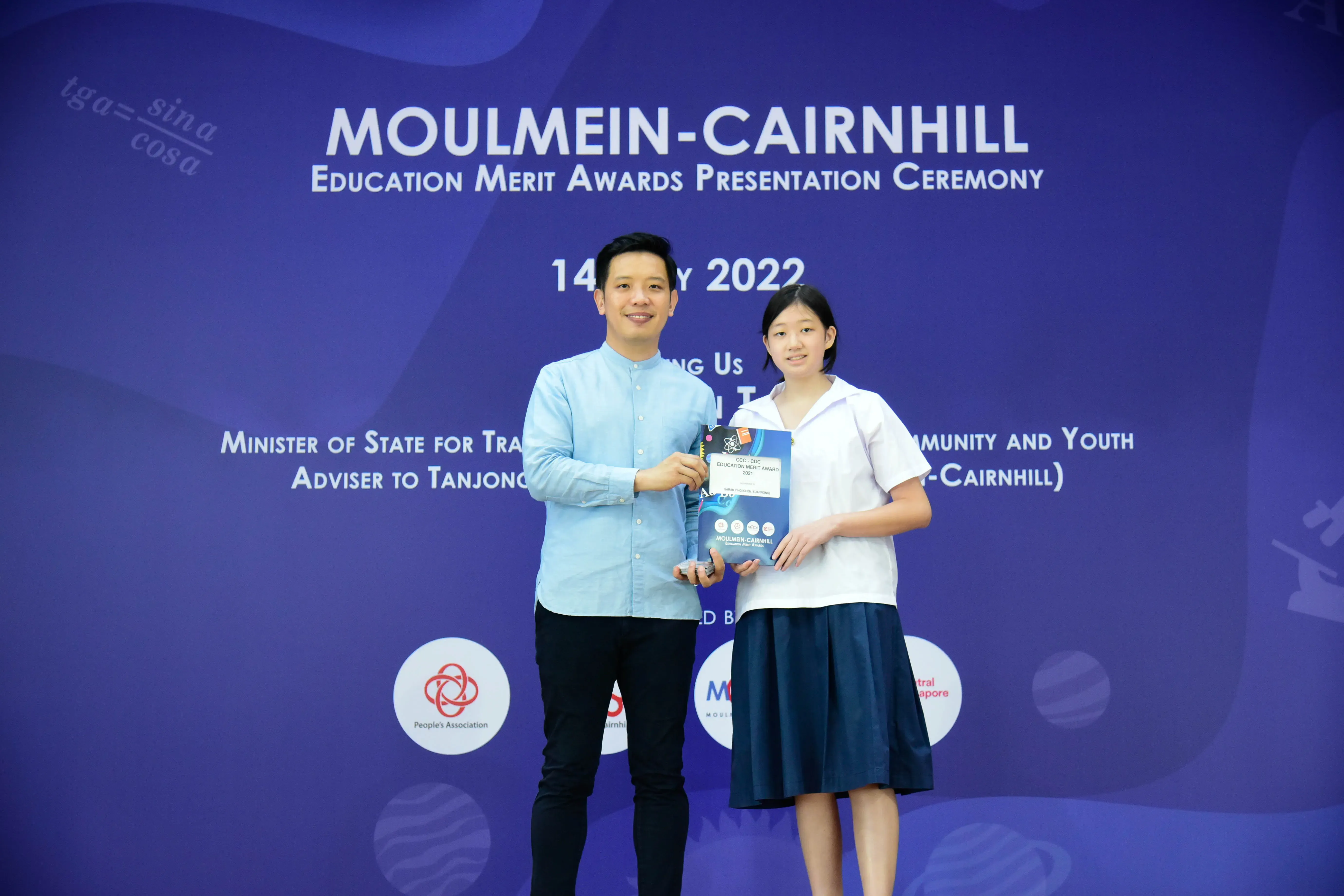 A man and a young girl hold an award together at the Moulmein-Cairnhill Education Merit Awards Ceremony 2022.