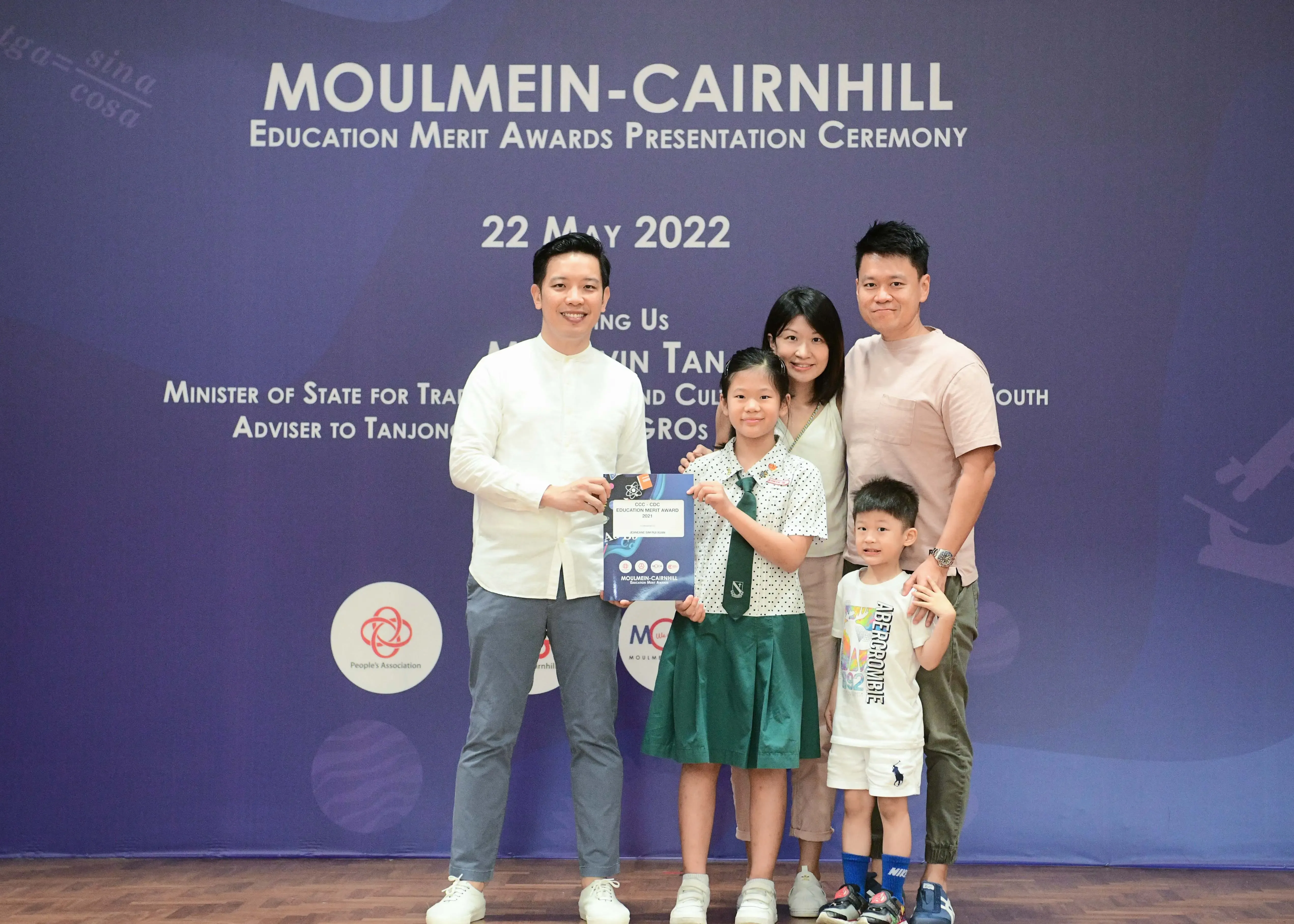 Five people pose at the Moulmein-Cairnhill Education Merit Awards ceremony on 22 May 2022, girl holding award certificate.