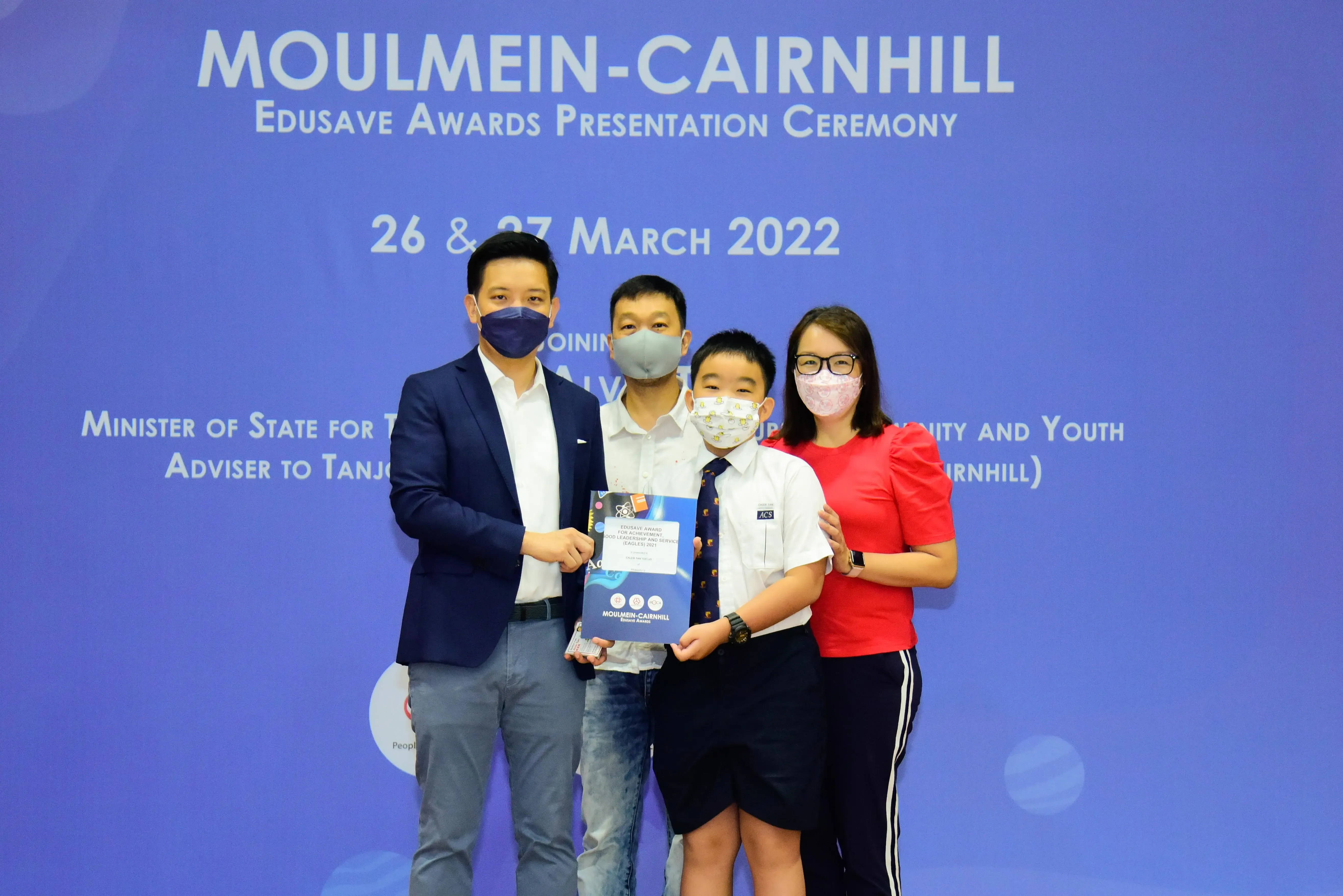 Four masked people pose at the Moulmein-Cairnhill Edusave Awards Presentation Ceremony on 26-27 March 2022.